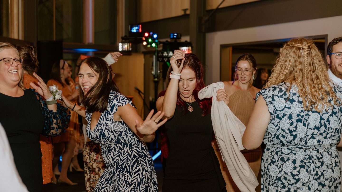 A group of people are dancing at a wedding reception.