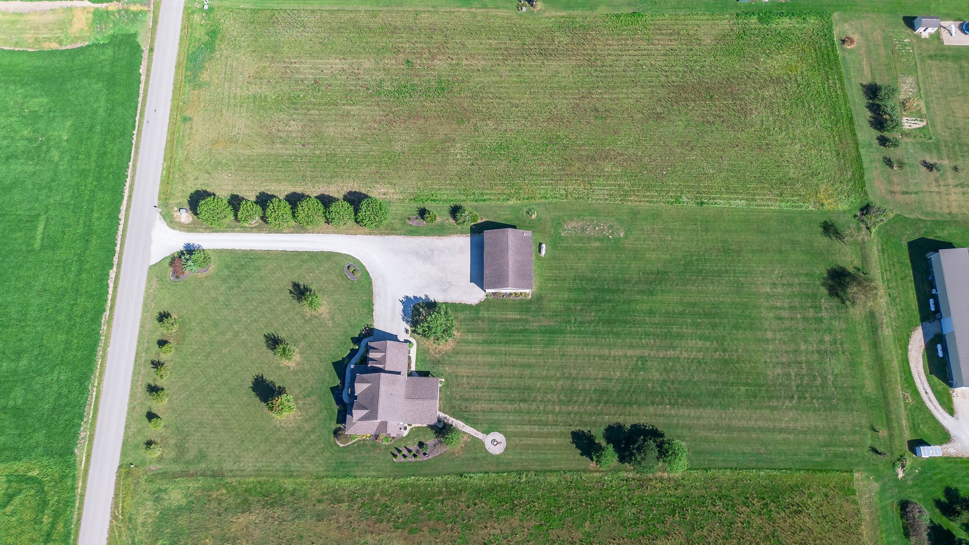 An aerial view of a house in the middle of a lush green field.