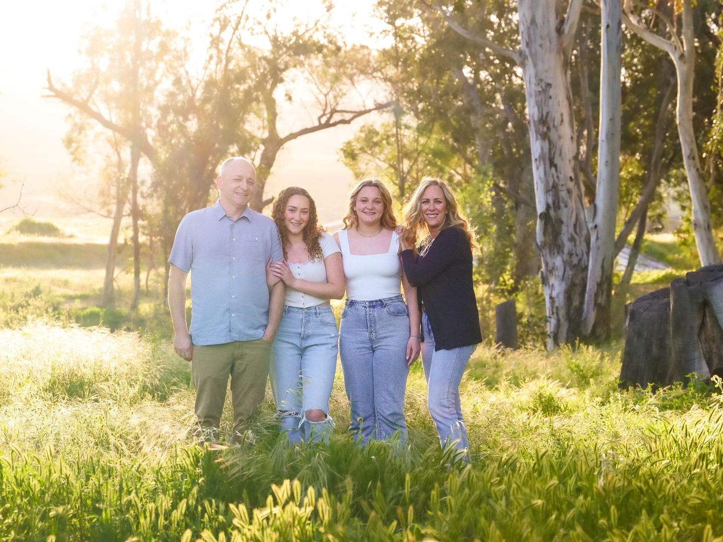 A family is posing for a picture in a field with trees in the background.