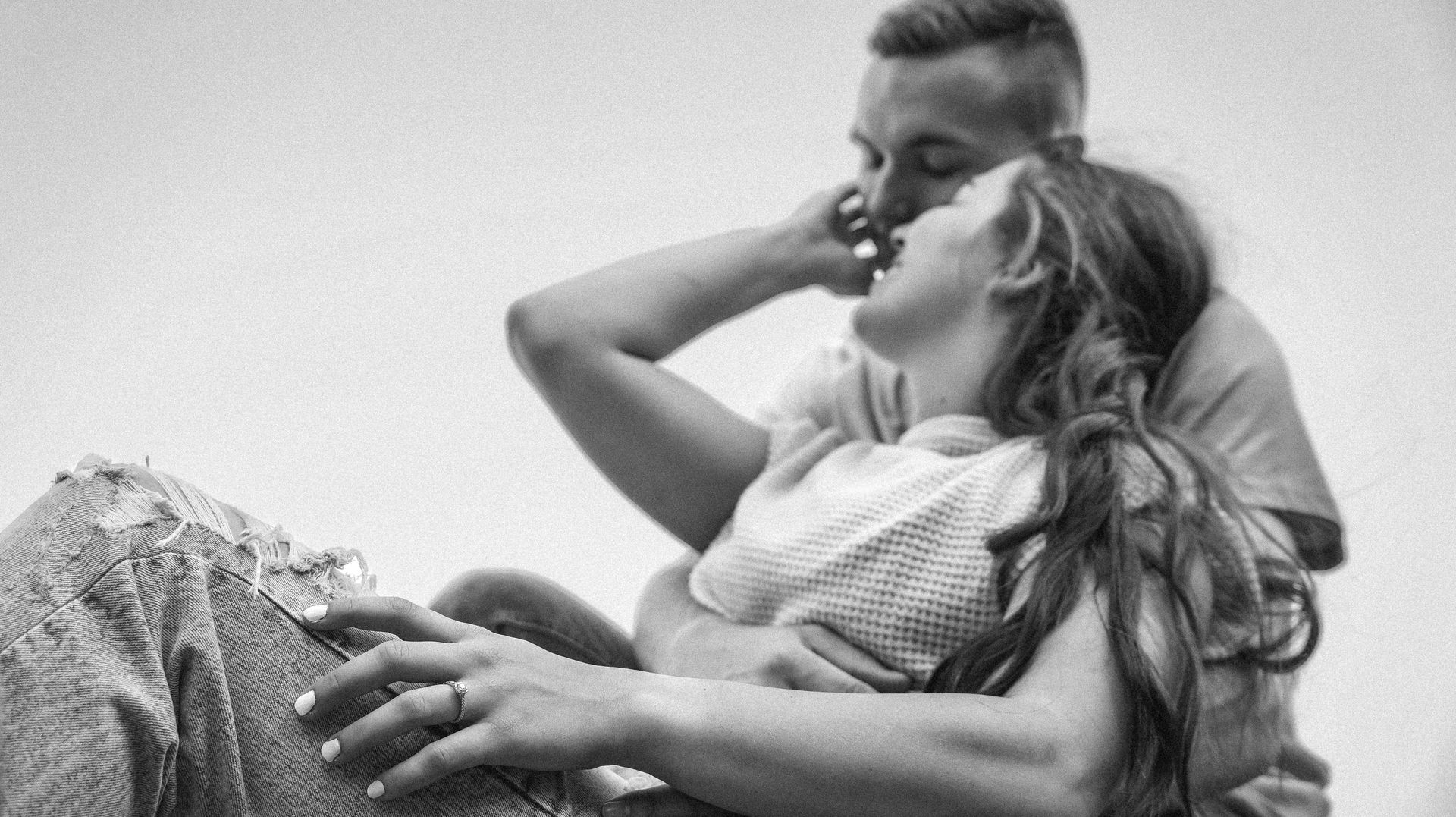 A man and a woman are hugging each other in a black and white photo.