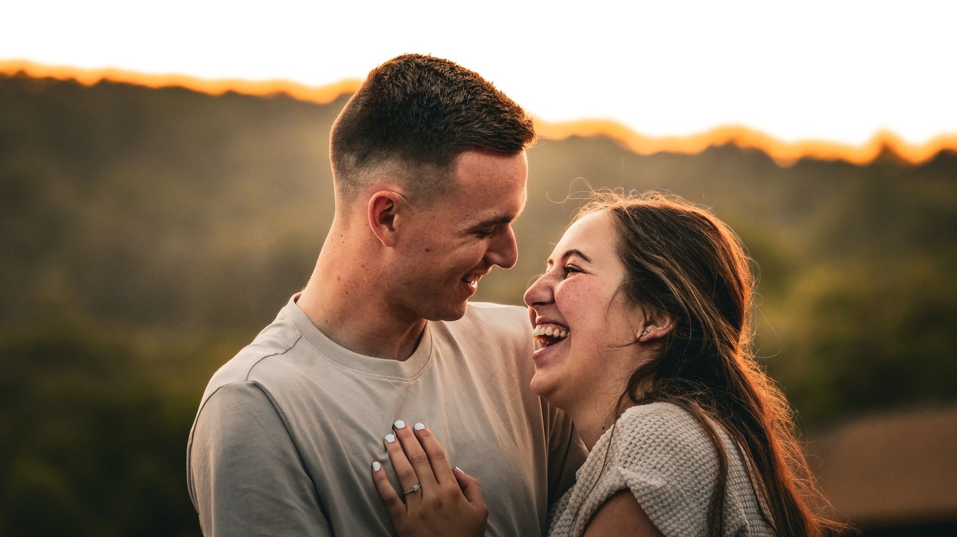 A man and a woman are laughing together and looking at each other.