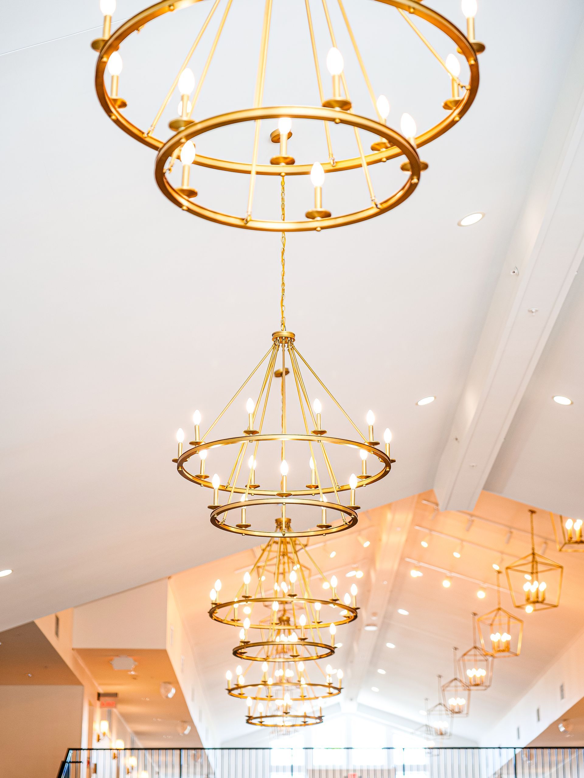 A row of gold chandeliers hanging from the ceiling of a room.