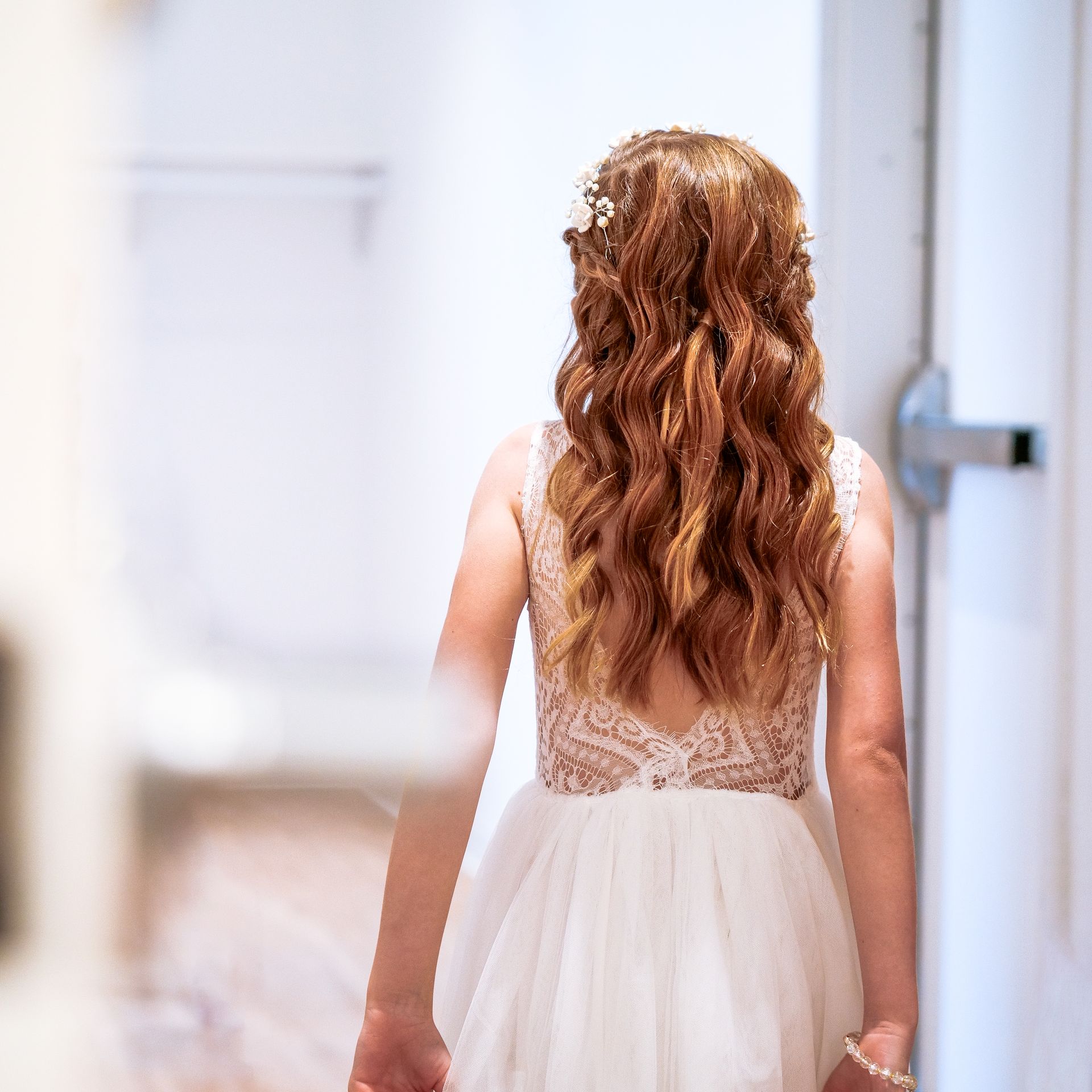 A woman in a white dress is walking down a hallway
