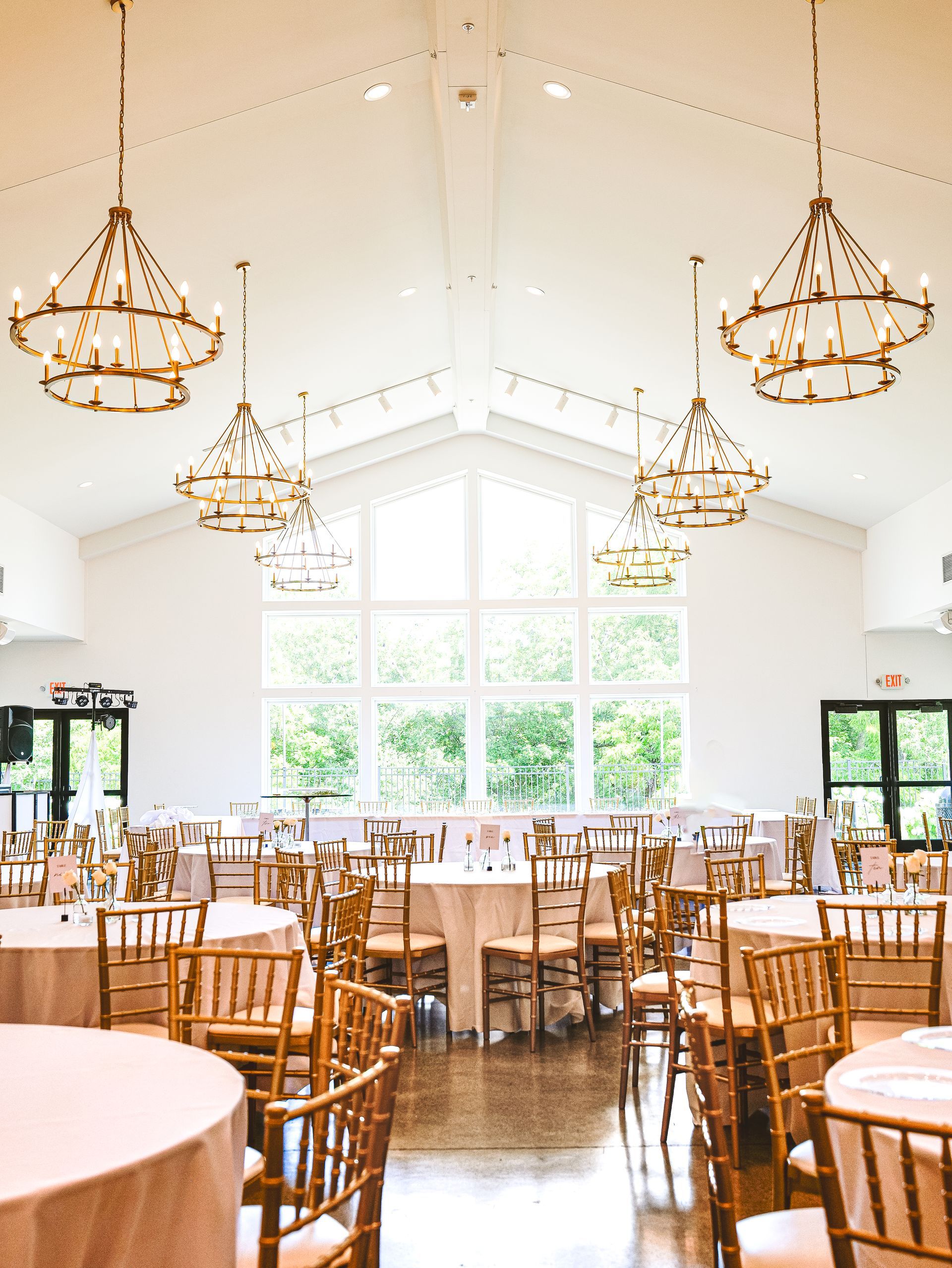 A large room with tables and chairs and chandeliers hanging from the ceiling.