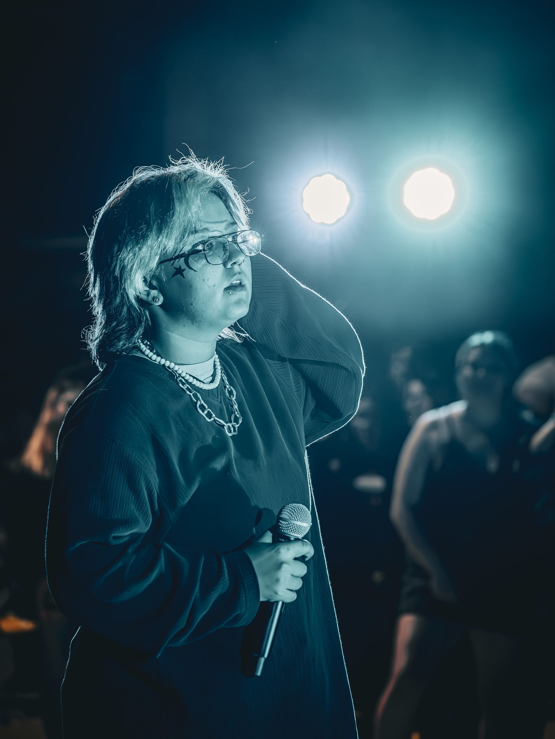 A man is singing into a microphone on a stage in front of a crowd.