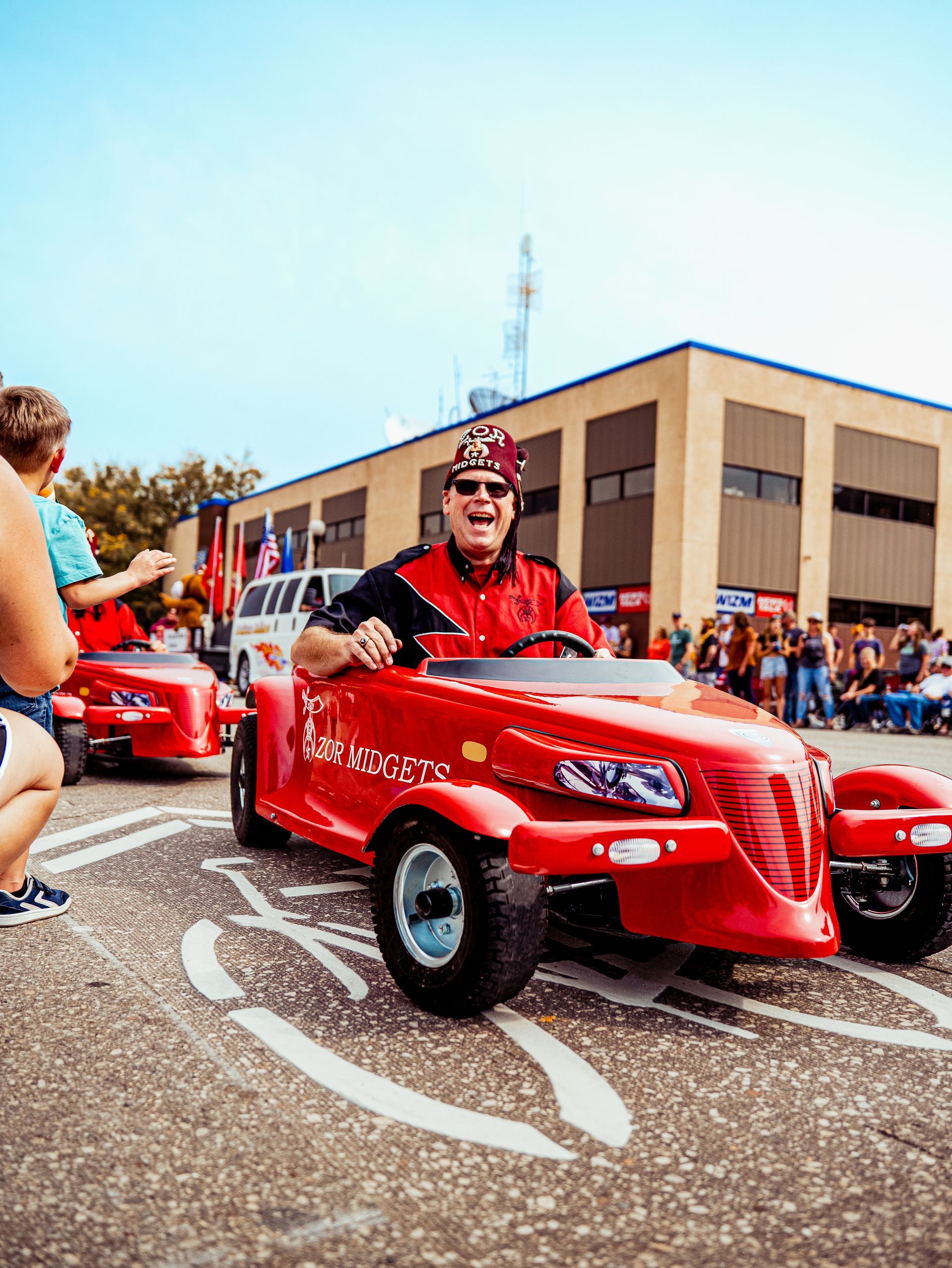 A man is driving a red lawn mower down a street.
