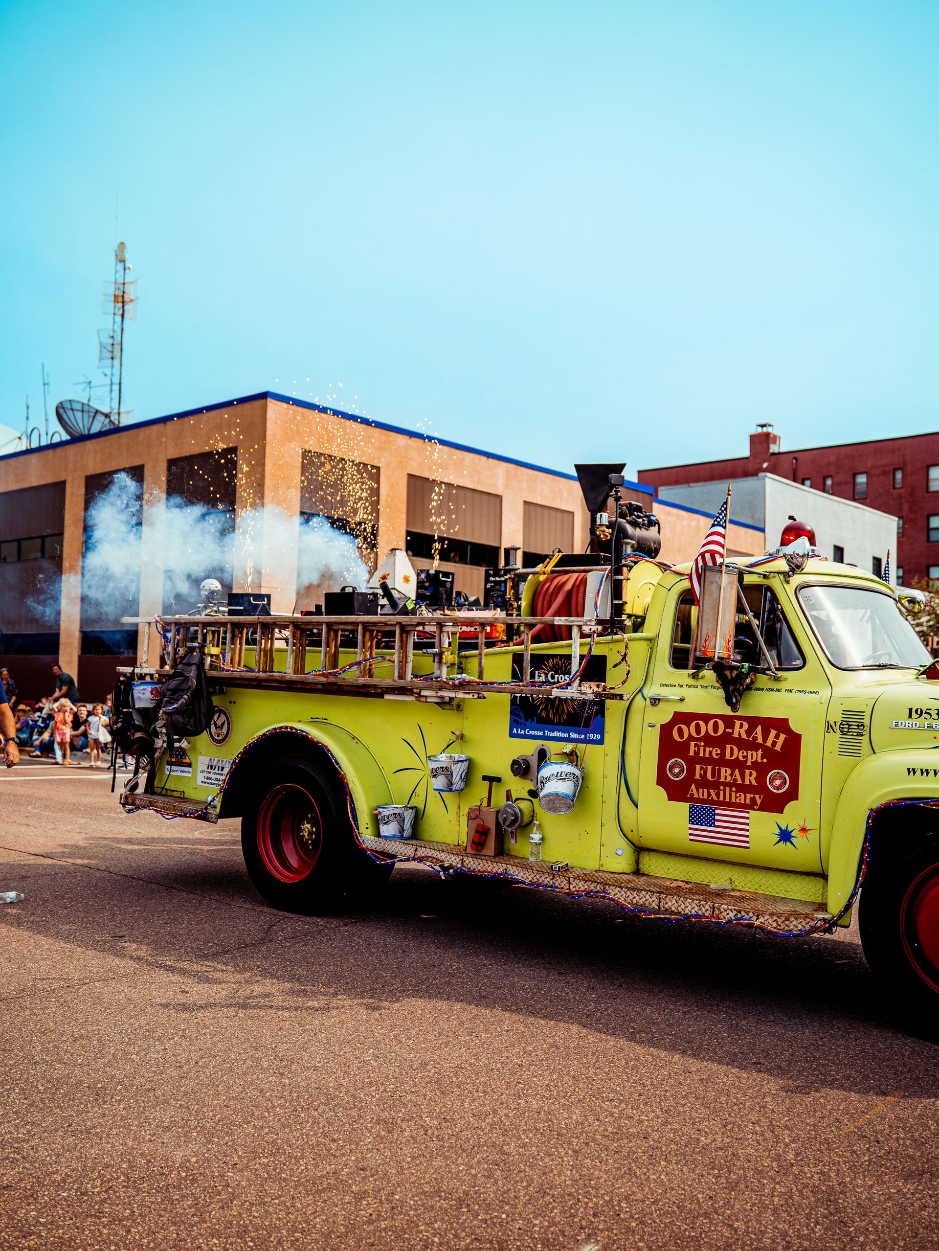 A yellow fire truck is driving down a street in front of a building.
