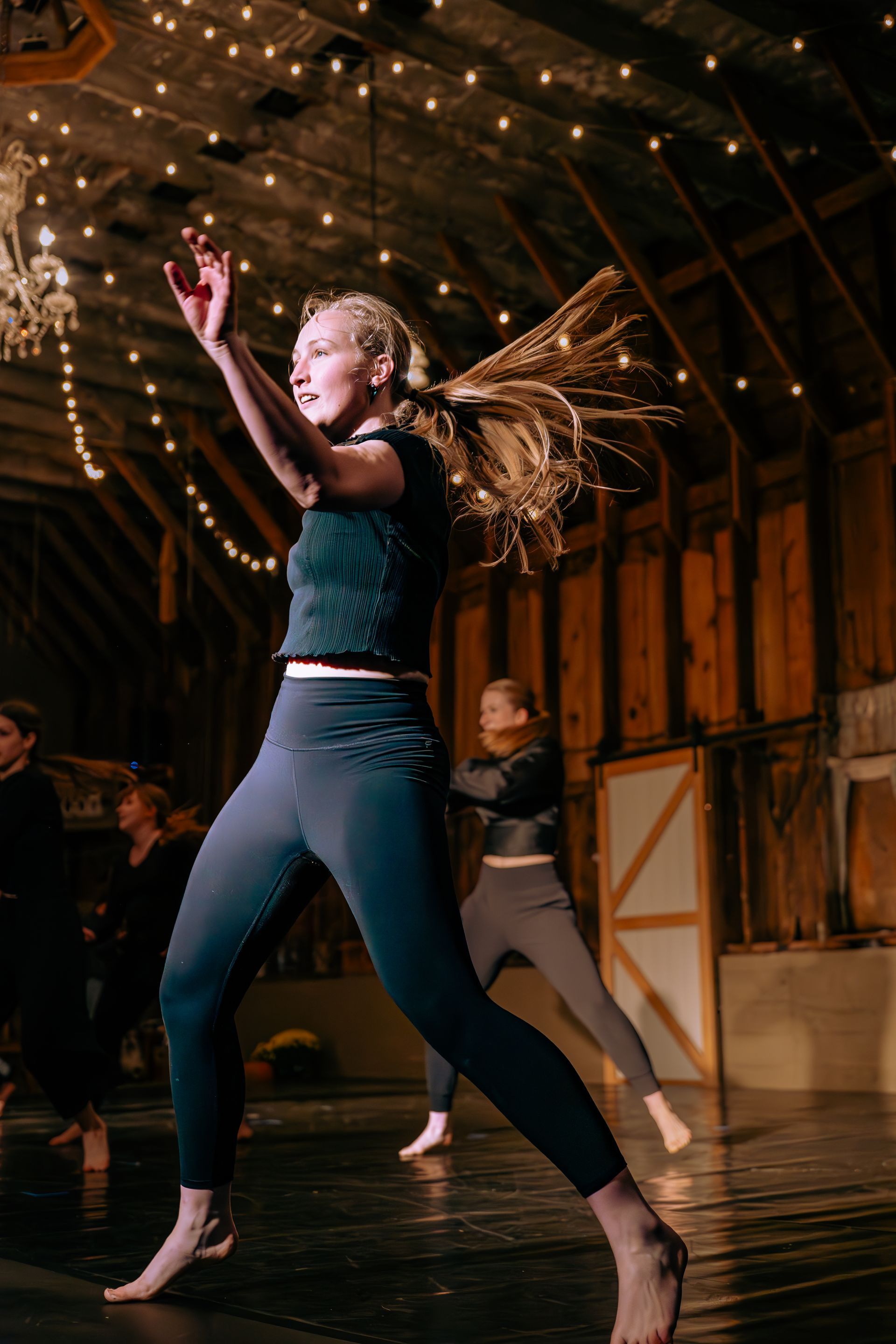 A group of people are dancing in a barn.
