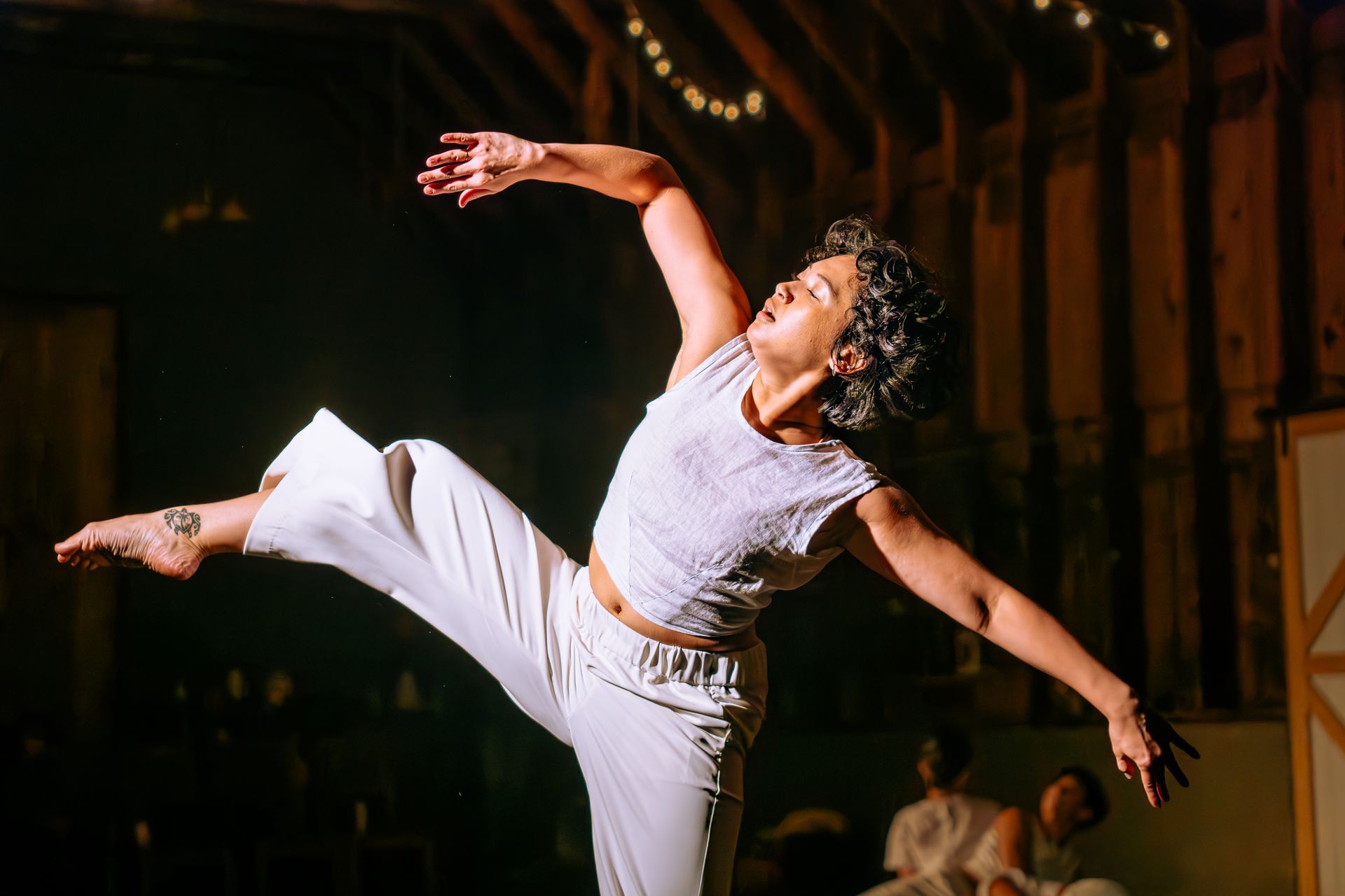 A woman is dancing in a dark room with her arms outstretched.