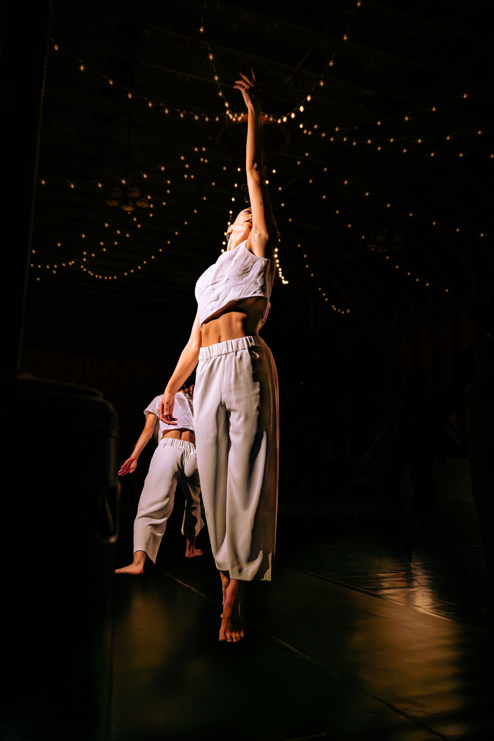 A couple of dancers are dancing on a stage in a dark room.