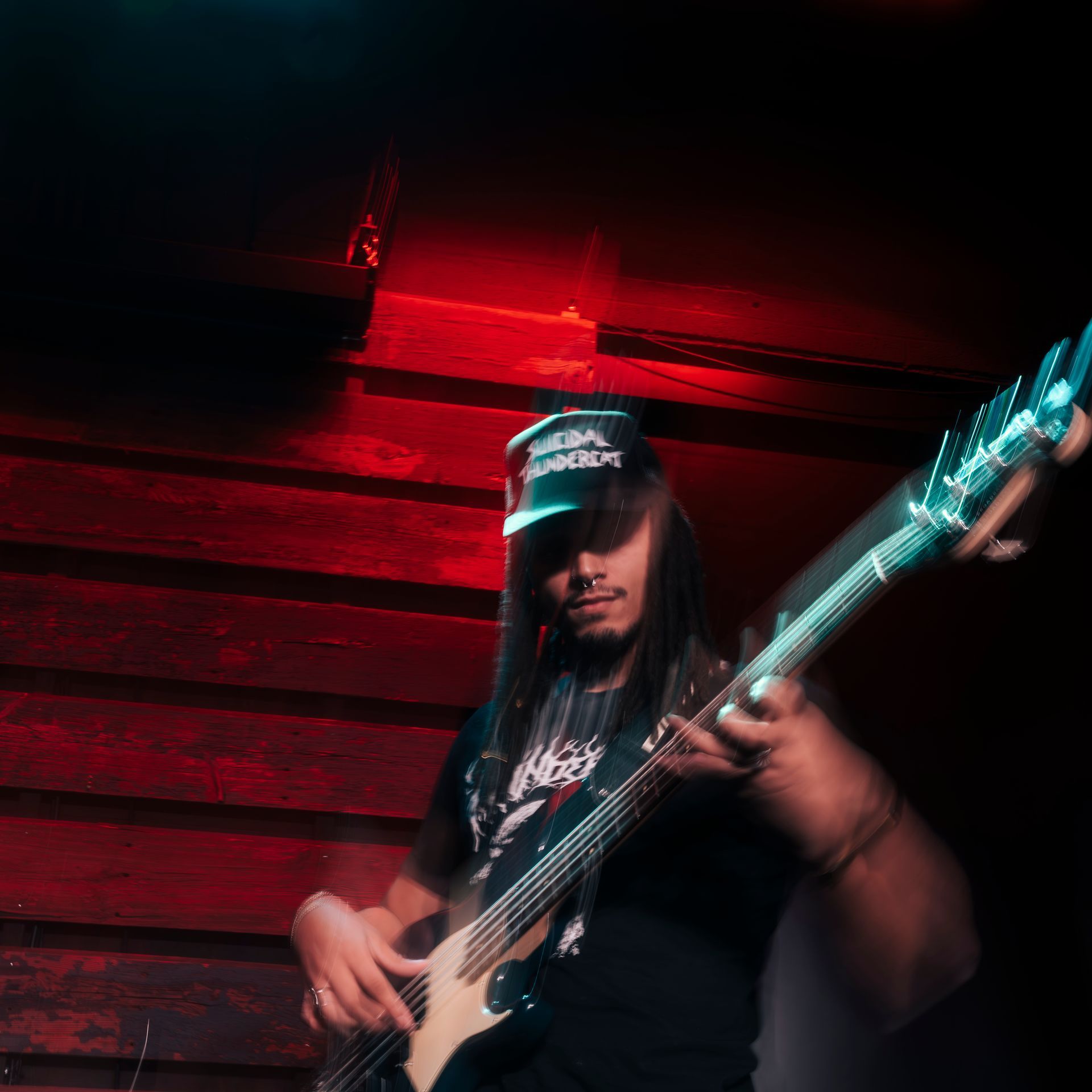 A man wearing a hat is playing a guitar