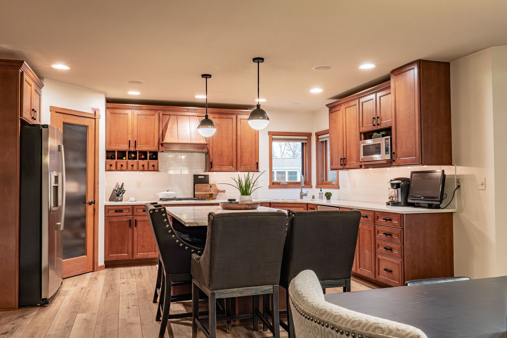 A kitchen with wooden cabinets , stainless steel appliances , a table and chairs.