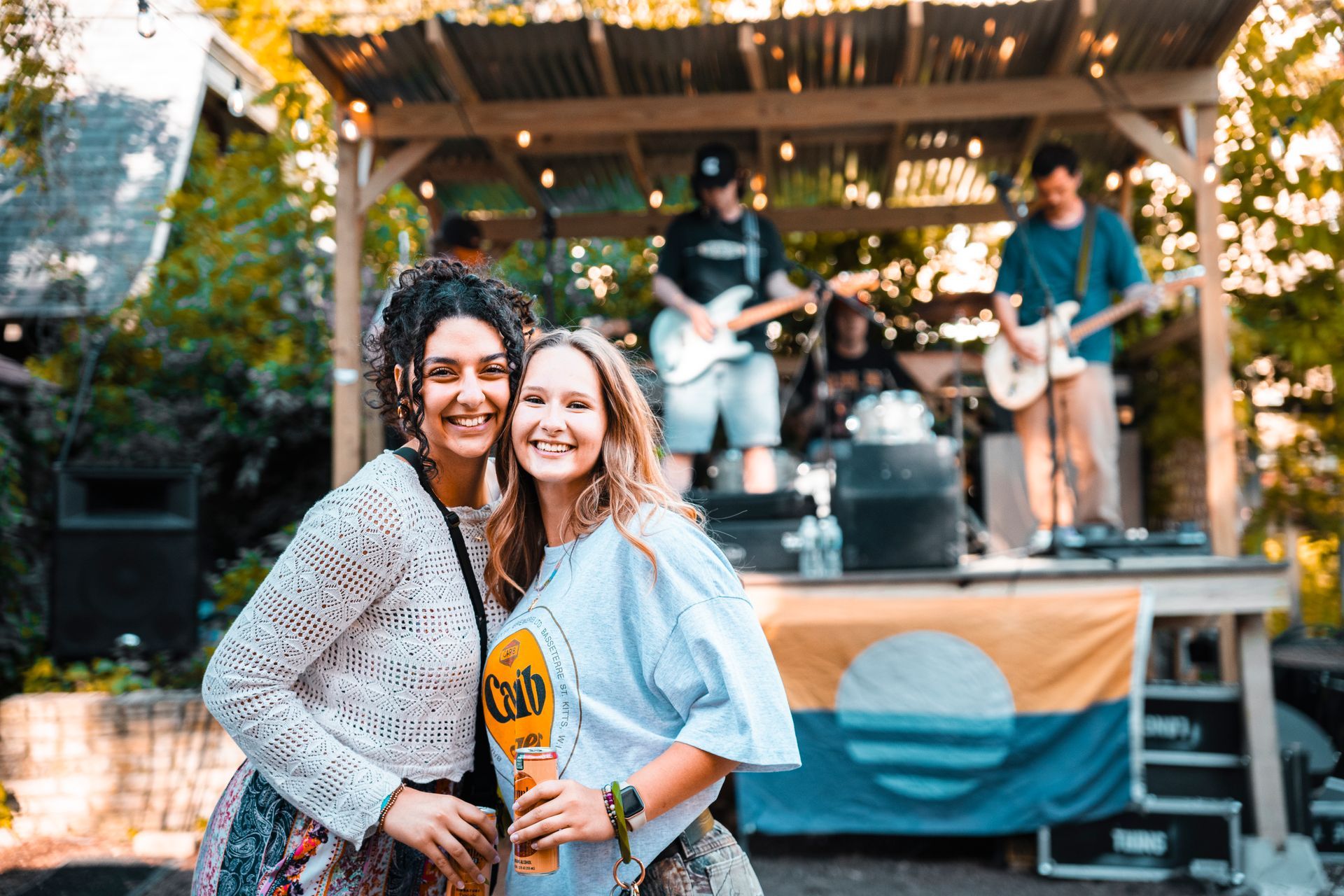 Two women are posing for a picture in front of a band on a stage.
