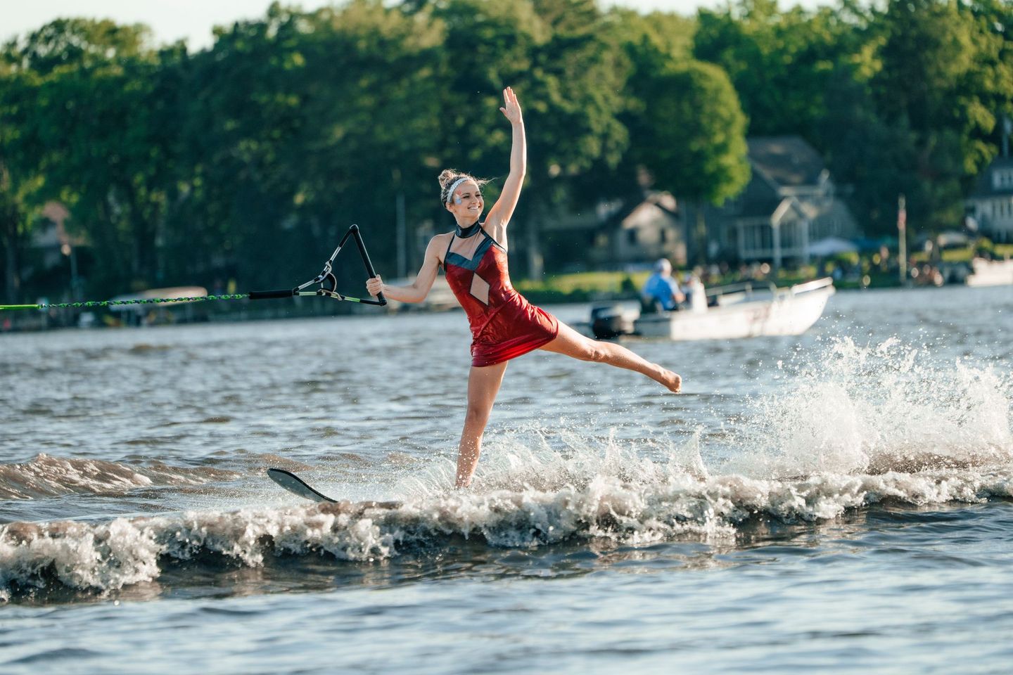 A woman in a red dress is water skiing on a lake.