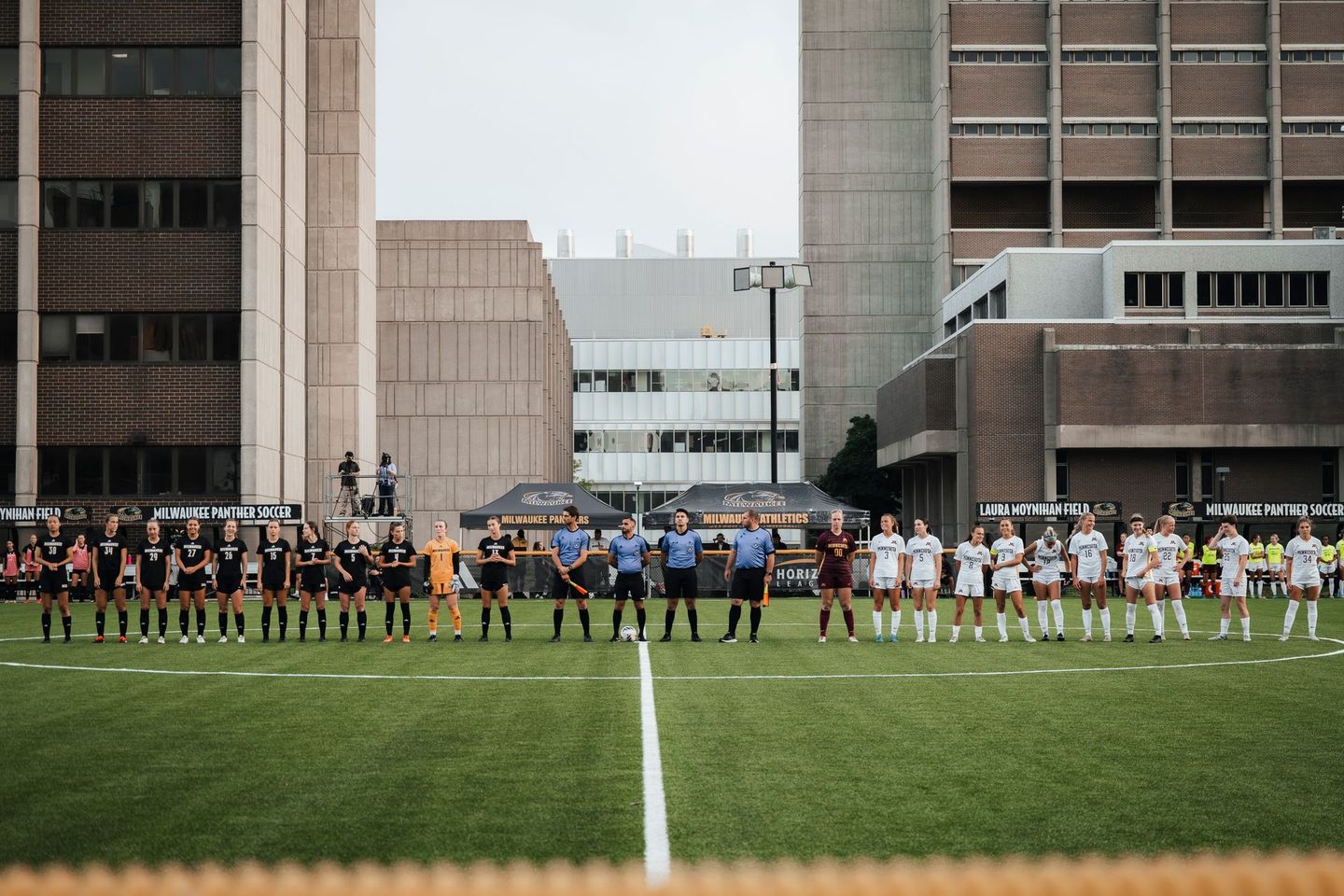 A group of people standing on top of a soccer field holding hands.