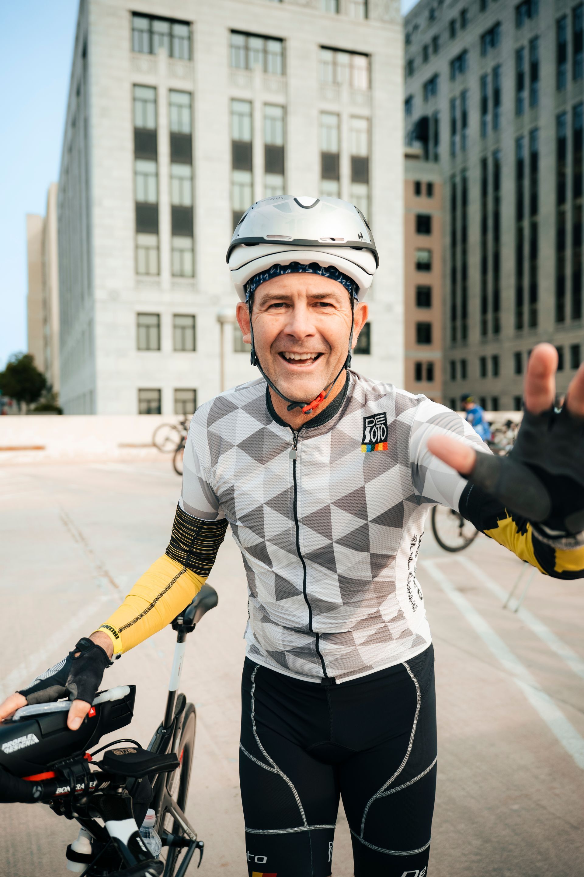 A man wearing a helmet is standing next to a bicycle and giving a thumbs up.