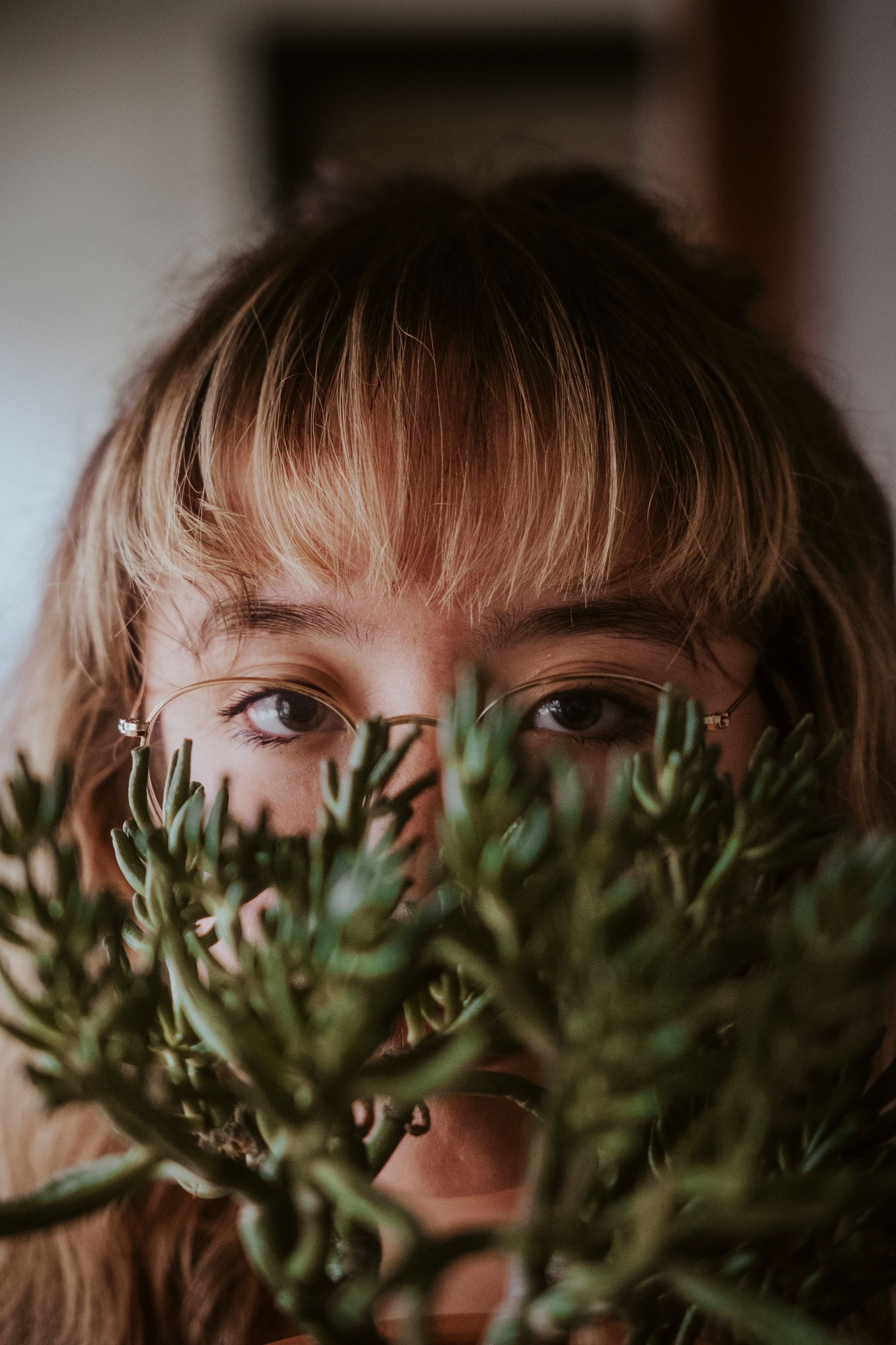 A woman is covering her face with a plant.