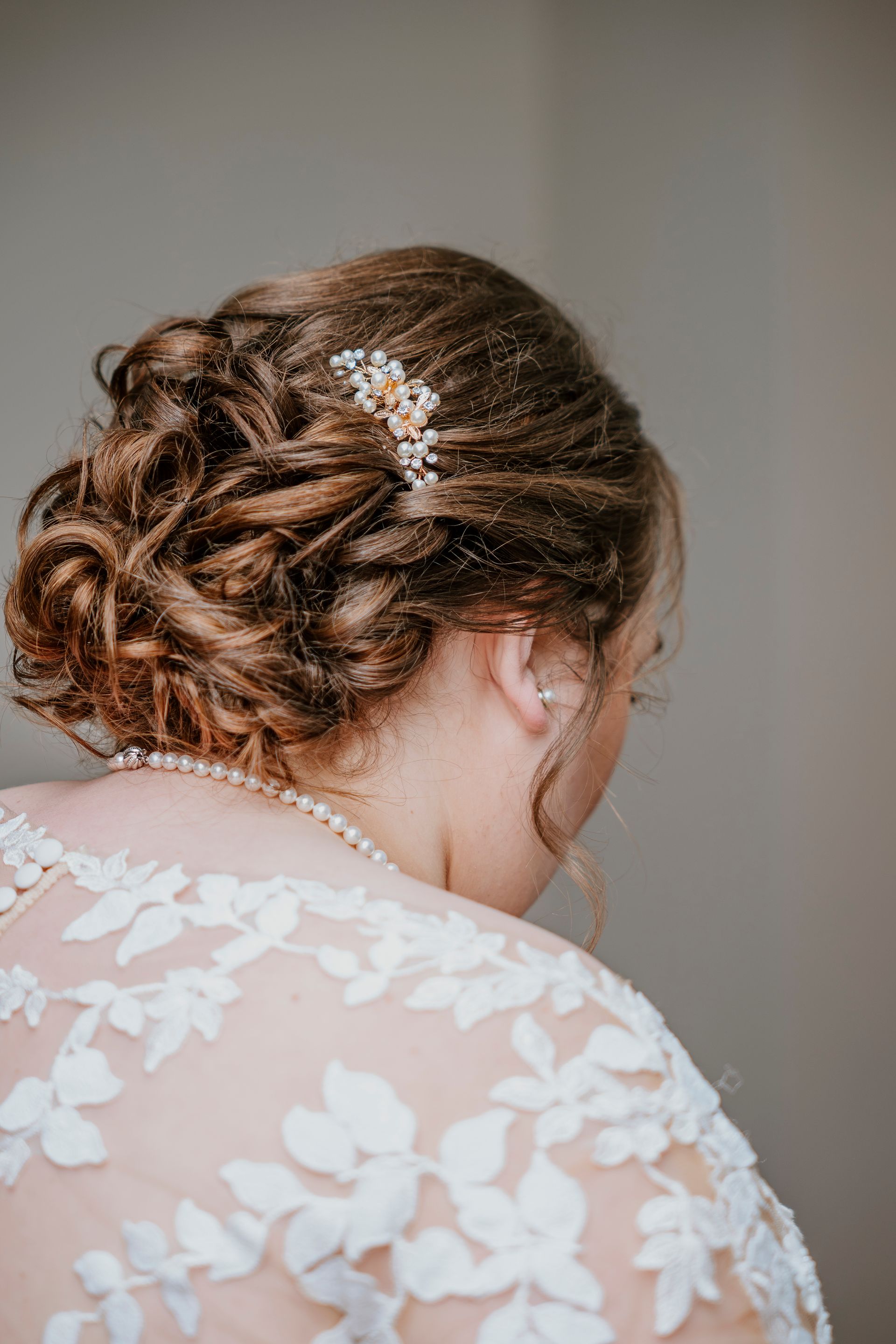 A woman in a wedding dress is looking down at her hair.