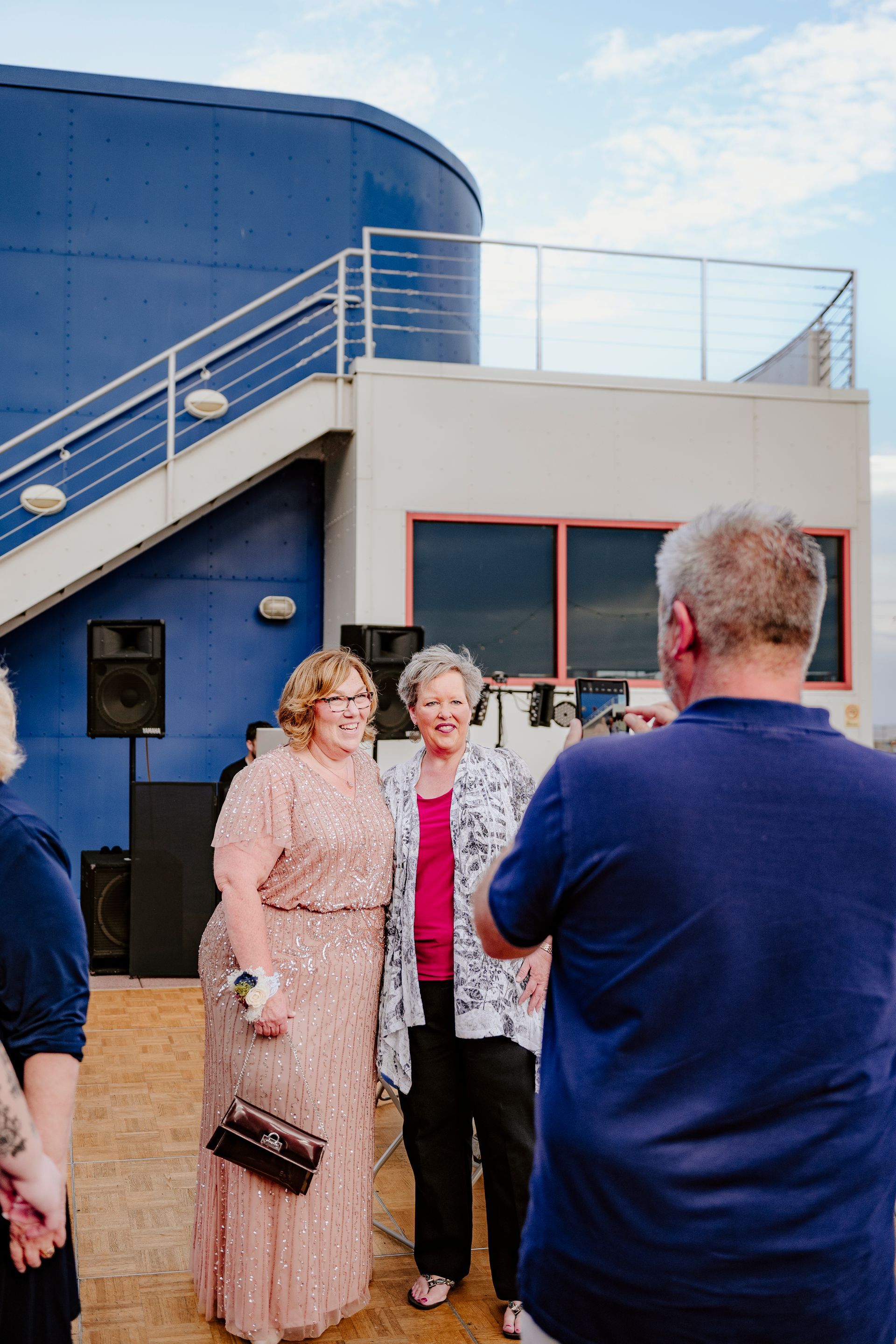 A man is taking a picture of two women standing next to each other in front of a building.