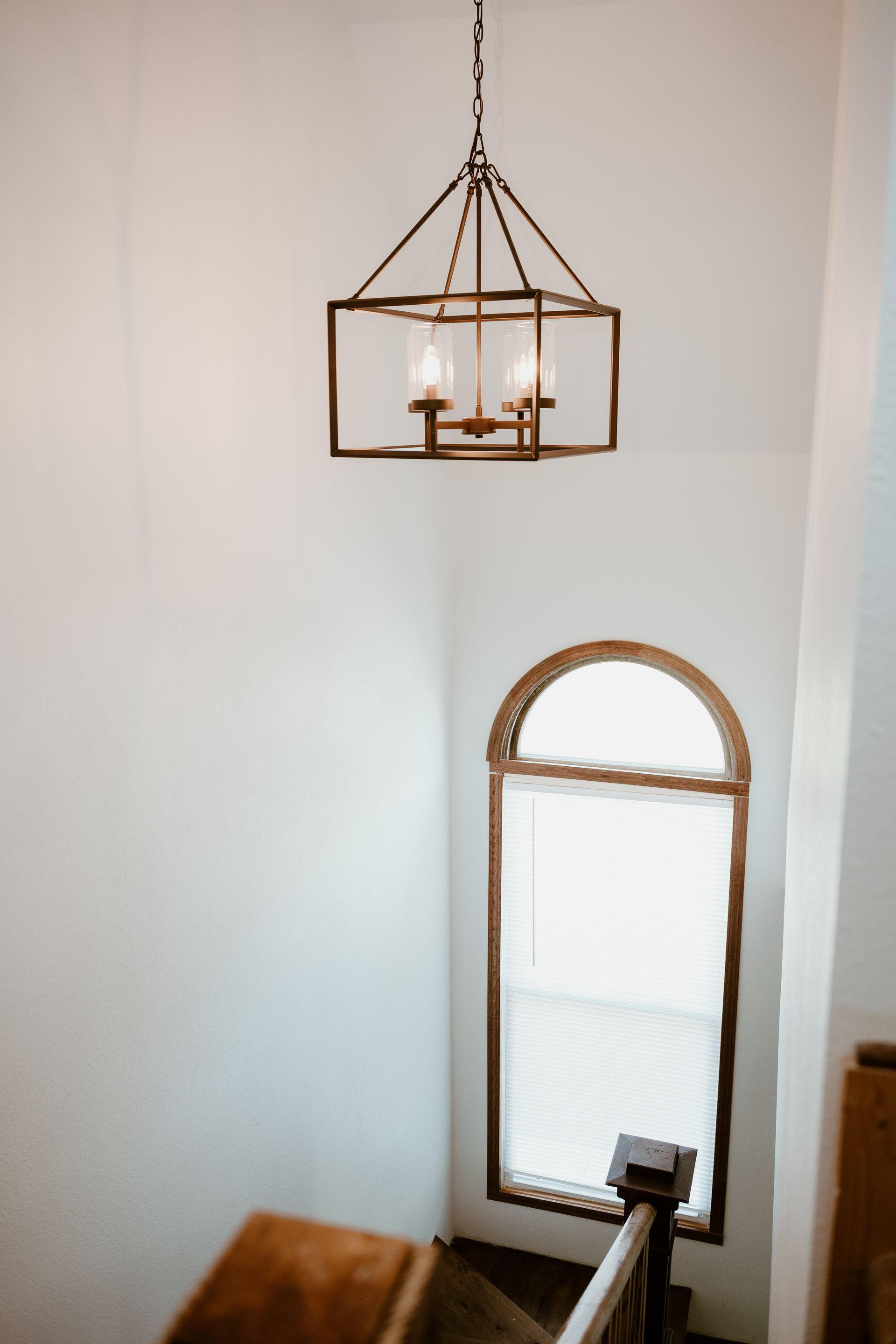 A staircase with a chandelier hanging from the ceiling and a window.