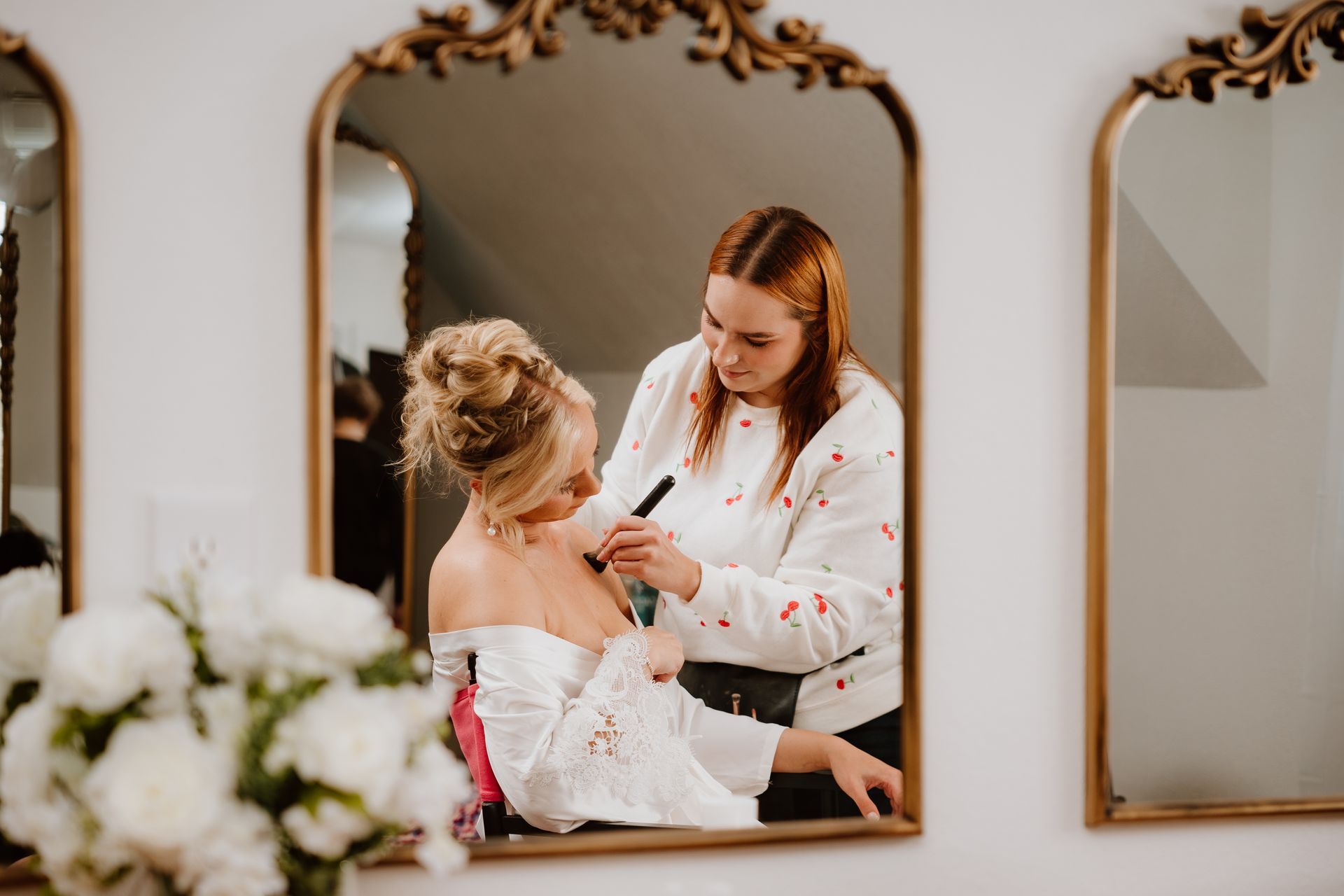 A woman is getting her hair done in front of a mirror.