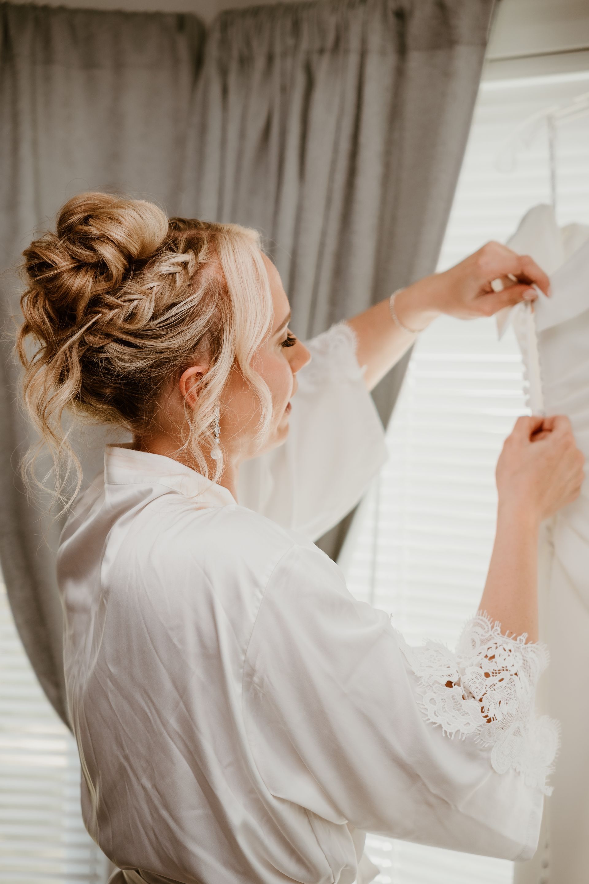 A woman in a white robe is putting on her wedding dress.