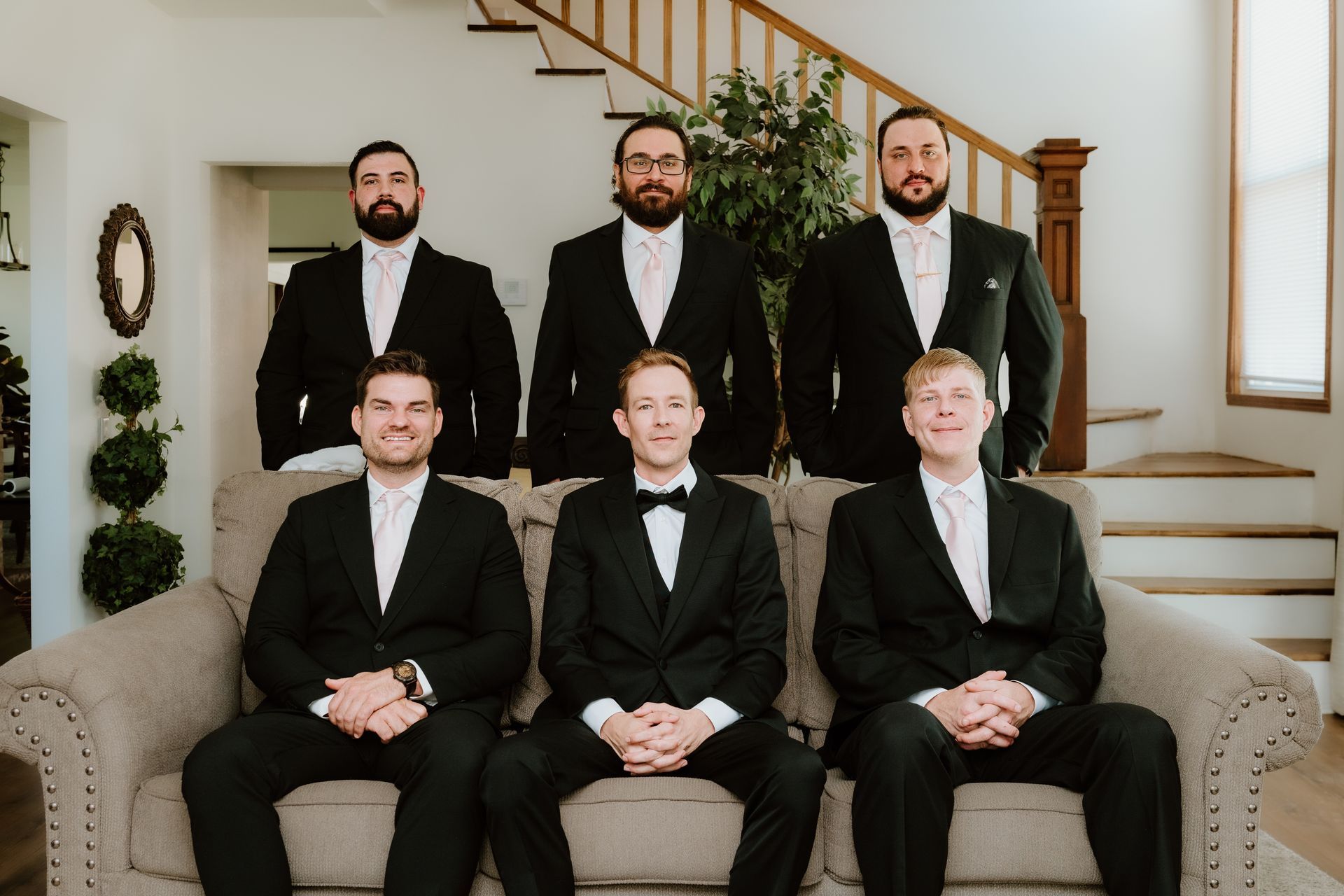 The groom and his groomsmen are posing for a picture while sitting on a couch.