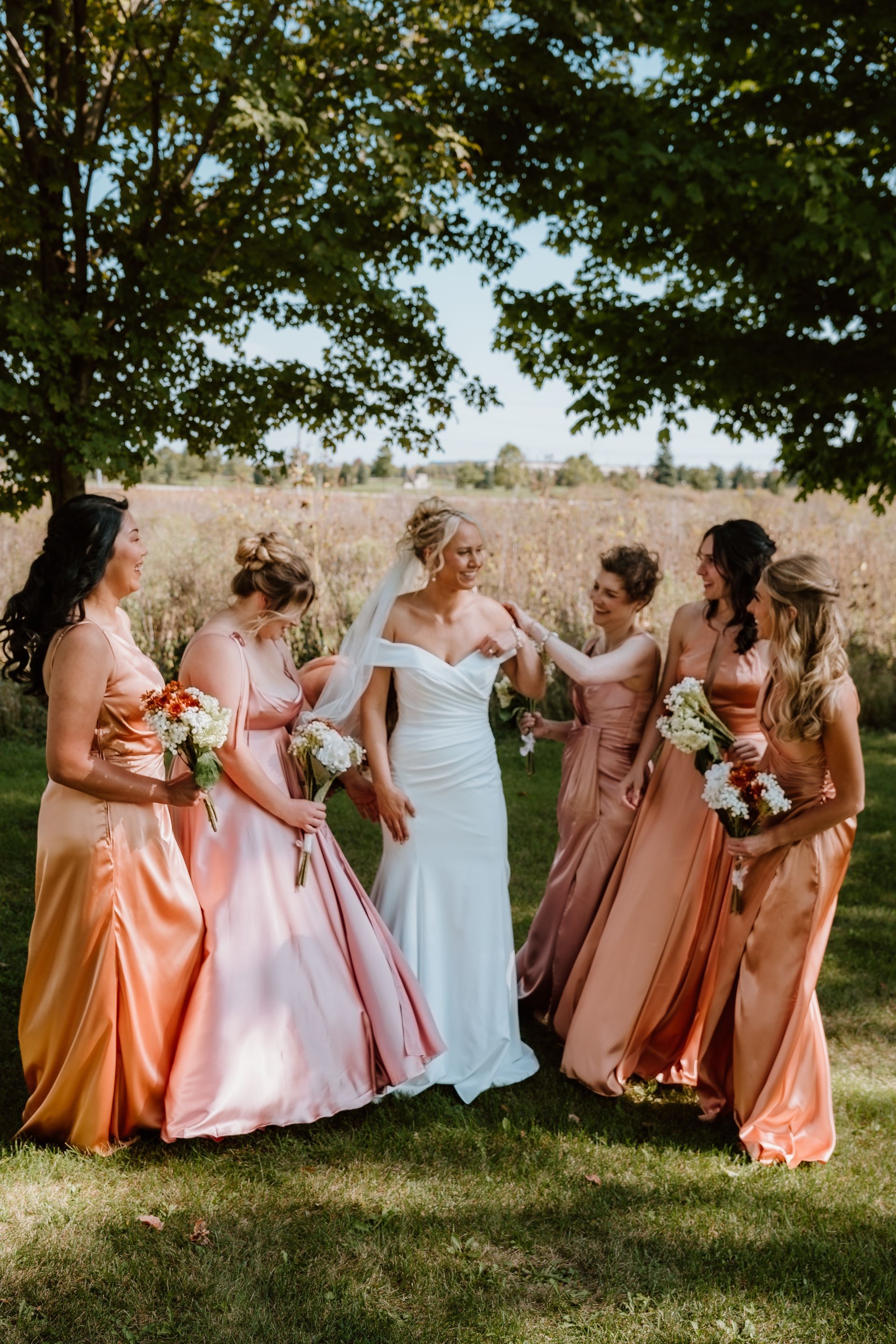 A bride and her bridesmaids are posing for a picture in a field.