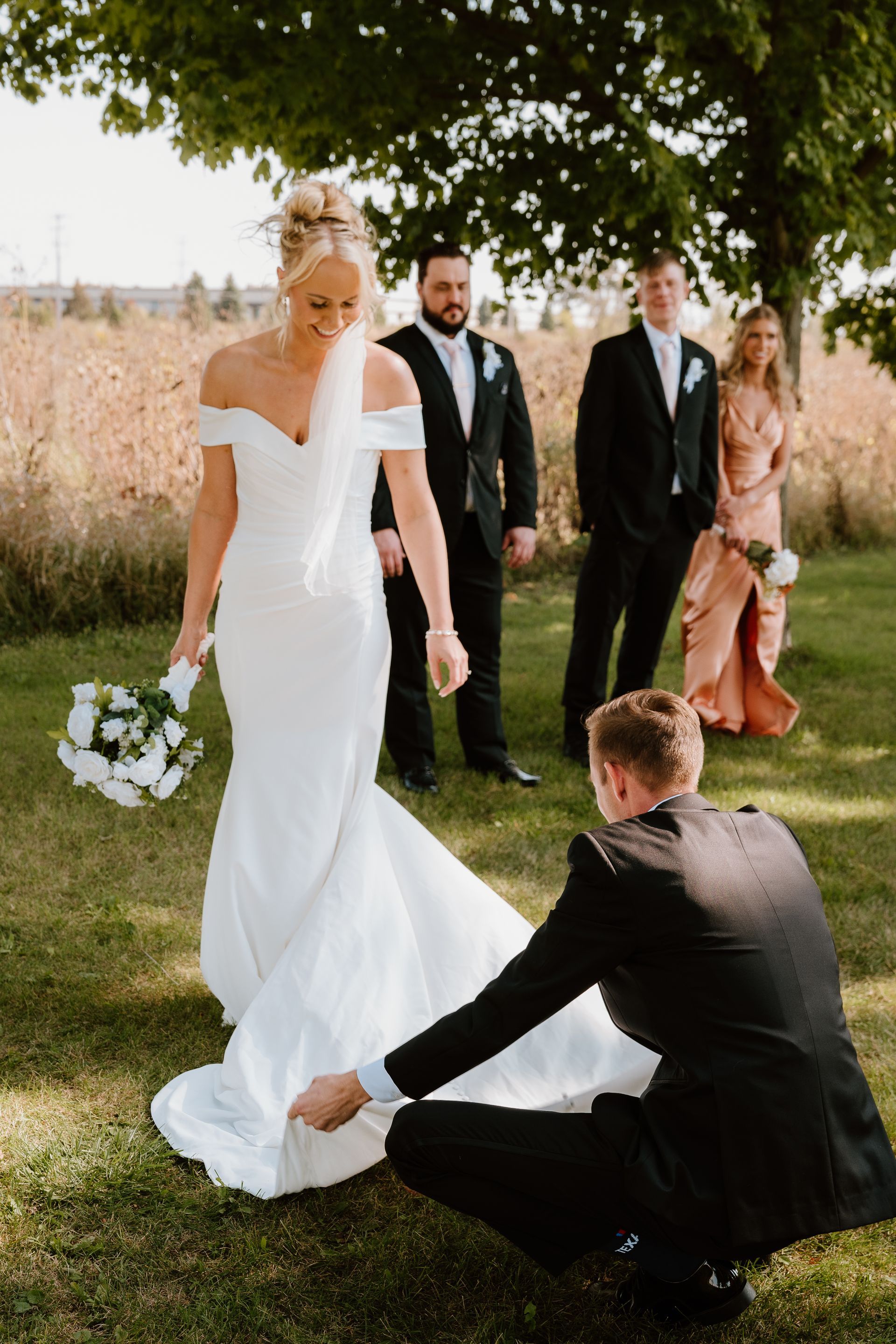 A bride and groom are standing in a field with their wedding party.