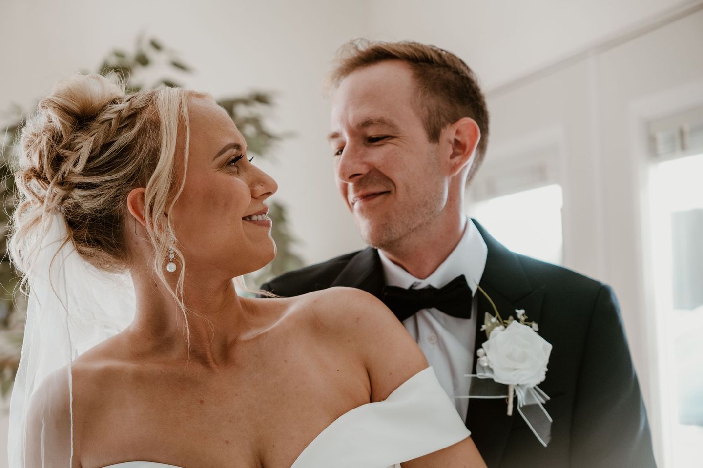 A bride and groom are looking at each other in a room.