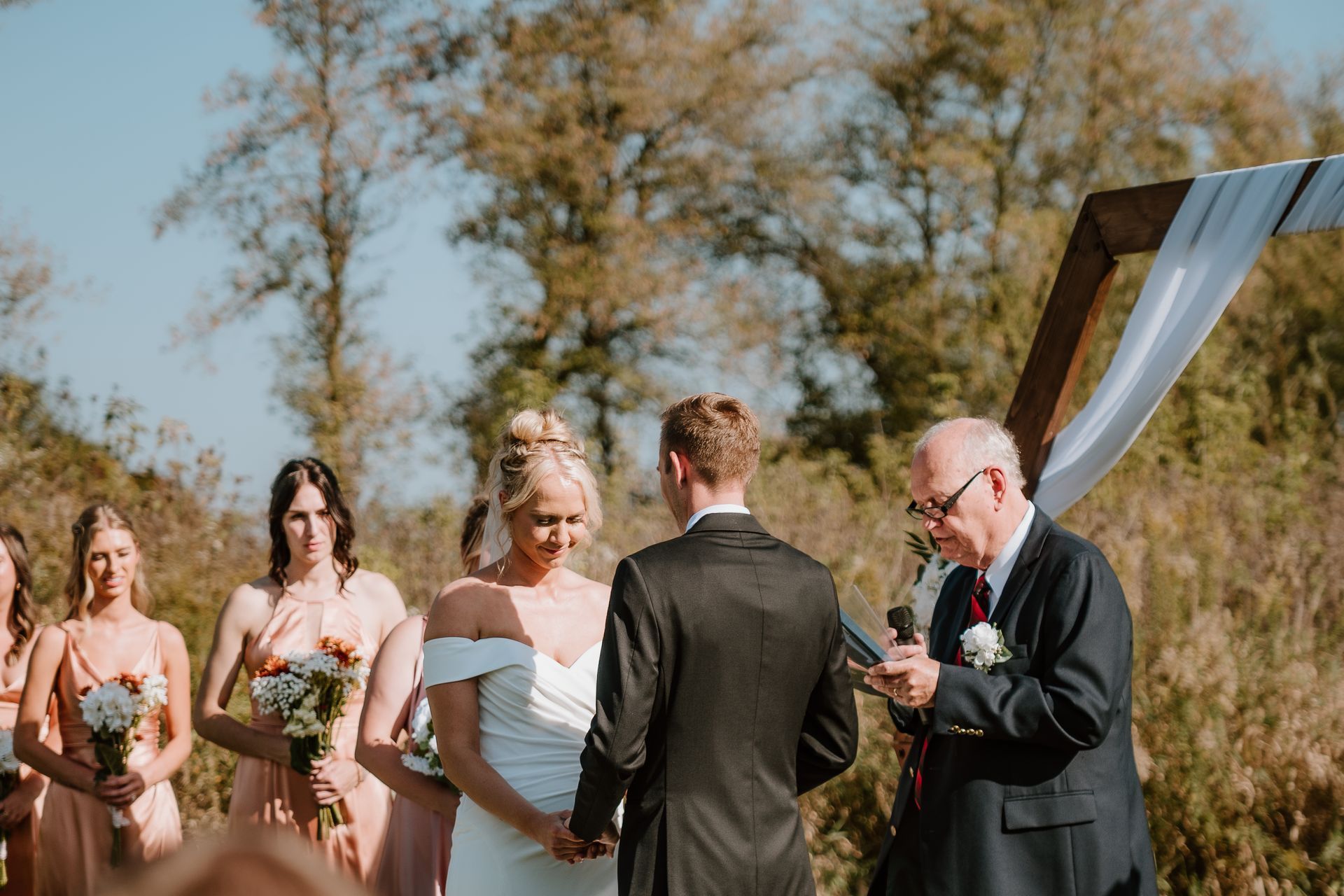 A bride and groom are holding hands during their wedding ceremony.