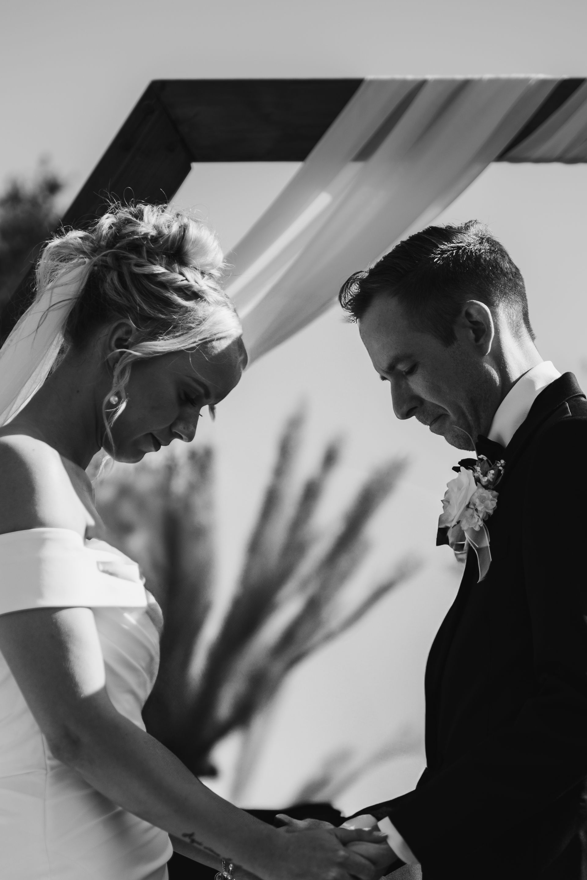 A black and white photo of a bride and groom holding hands