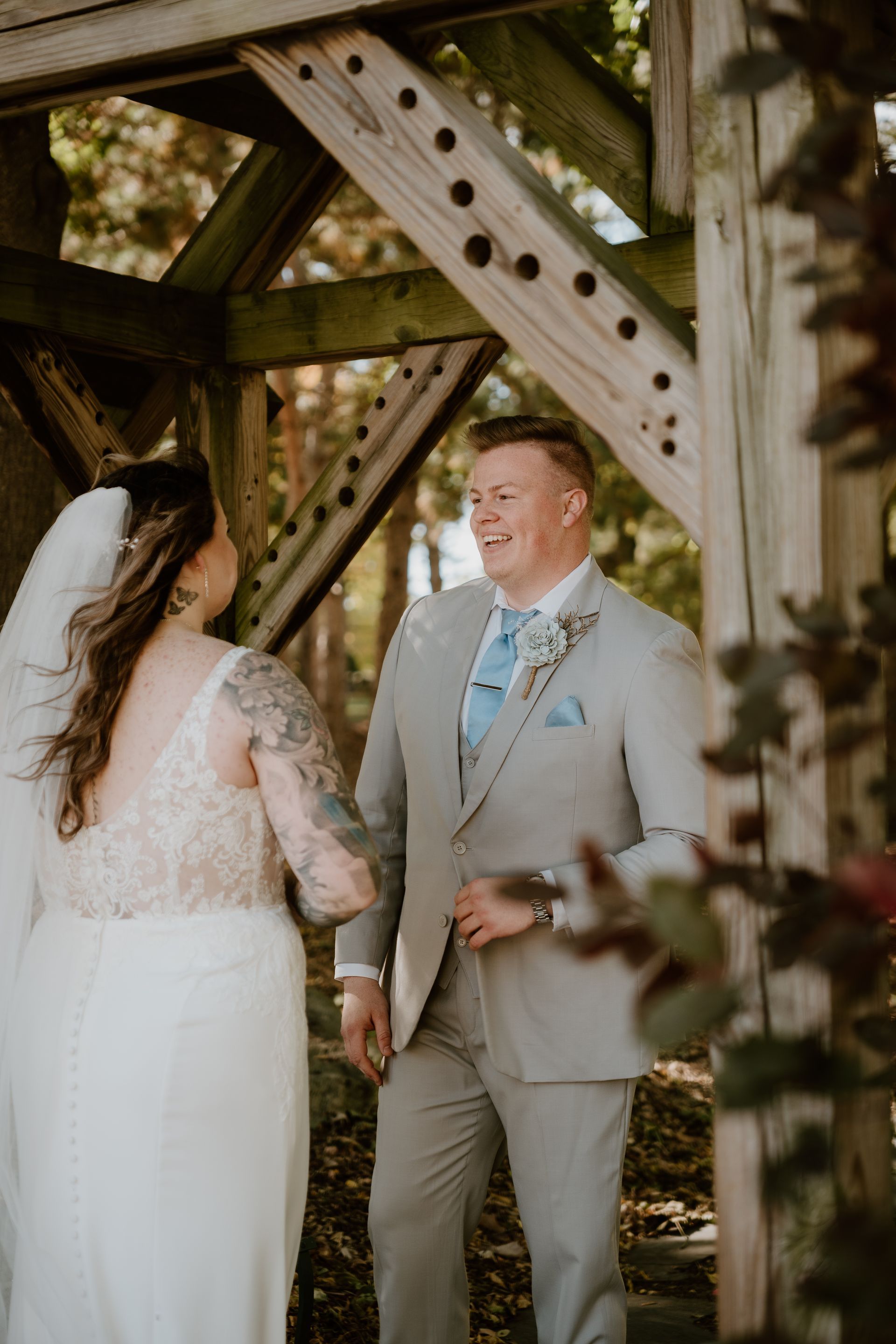 A bride and groom are standing next to each other under a bridge.