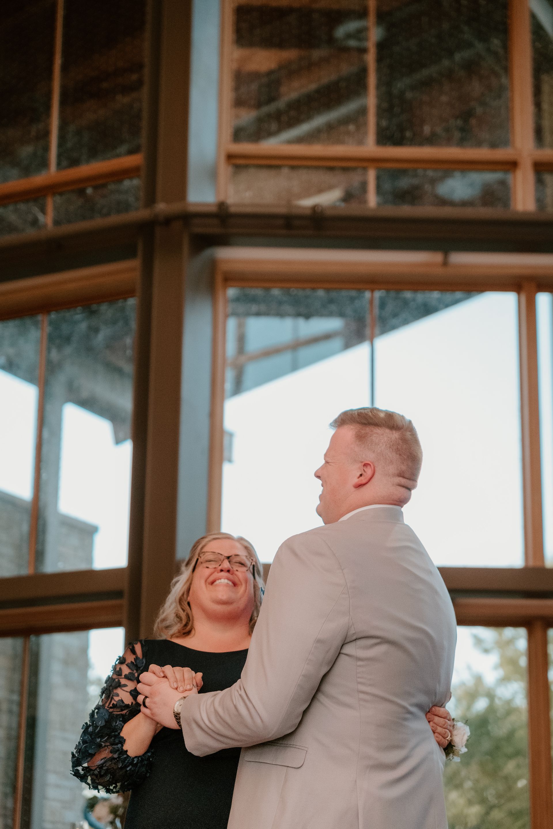 A man and a woman are dancing in front of a large window.
