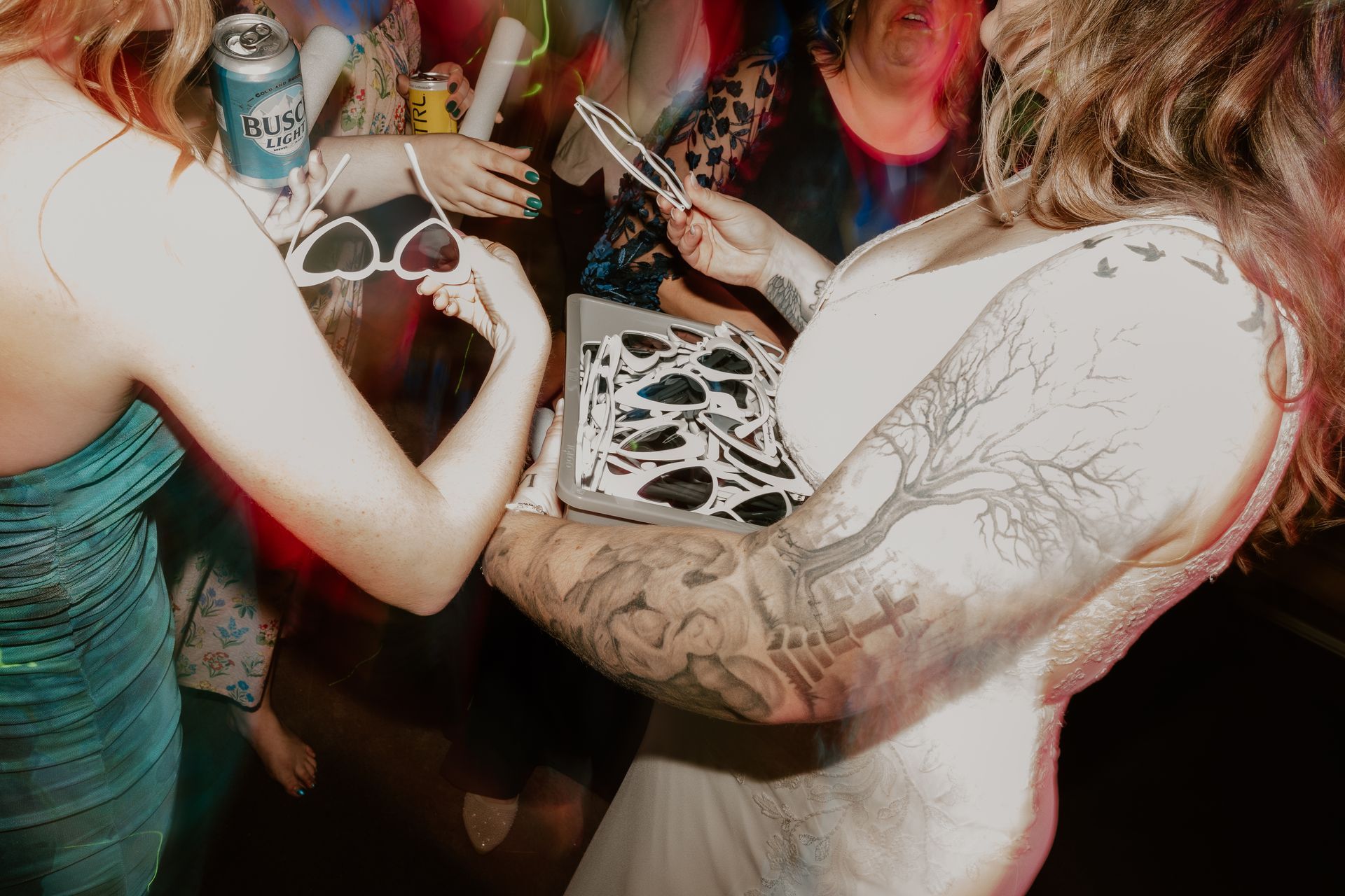 A woman with a tattoo on her arm is holding a box of pizza.