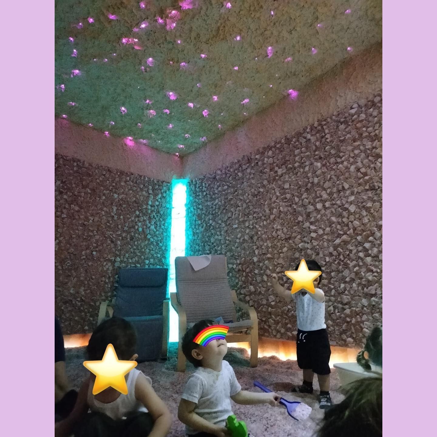 Bambini in una stanza per la terapia del sale con soffitto luminoso e pareti in pietra. Un bambino tiene in mano un giocattolo, gli altri sono seduti.