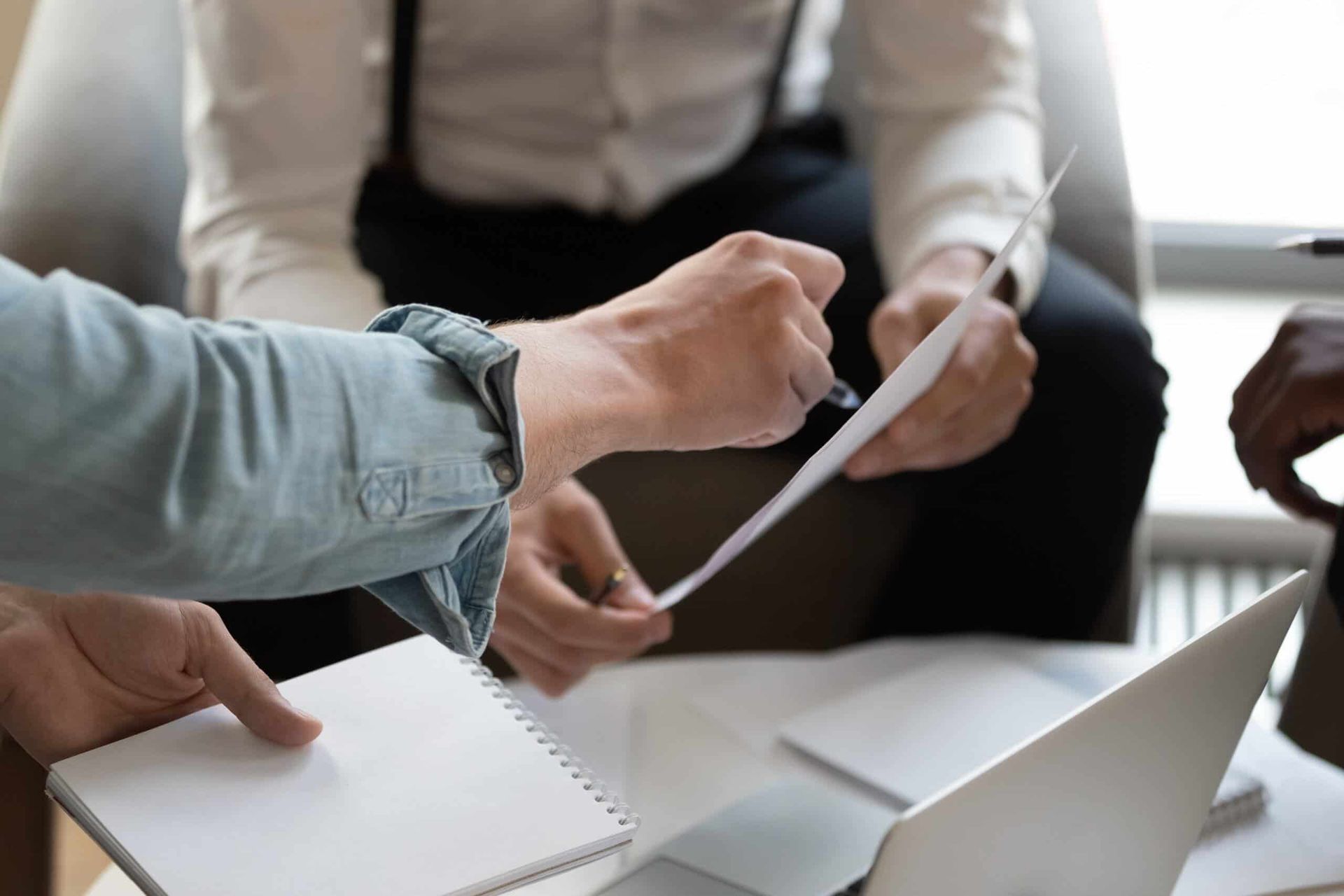 A Group of People Are Sitting Around a Table Looking at A Piece of Paper — Blue Orchid Accounting In Woongarrah, NSW