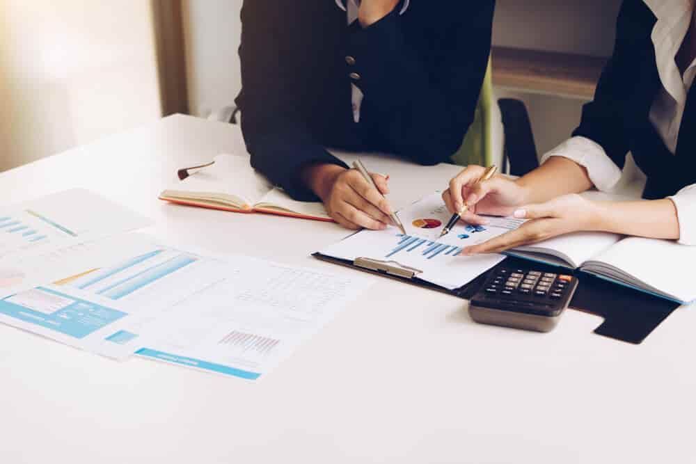 Two People Are Sitting at A Table Looking at Papers and A Calculator — Blue Orchid Accounting In Woongarrah, NSW