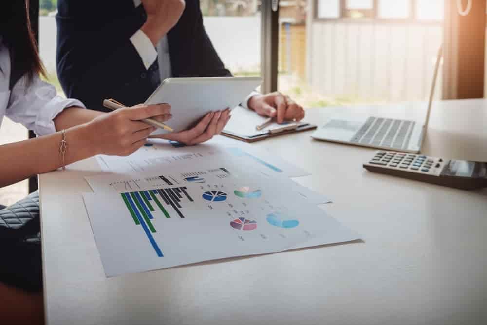 A Man and A Woman Are Sitting at A Table Looking at A Tablet — Blue Orchid Accounting In Woongarrah, NSW