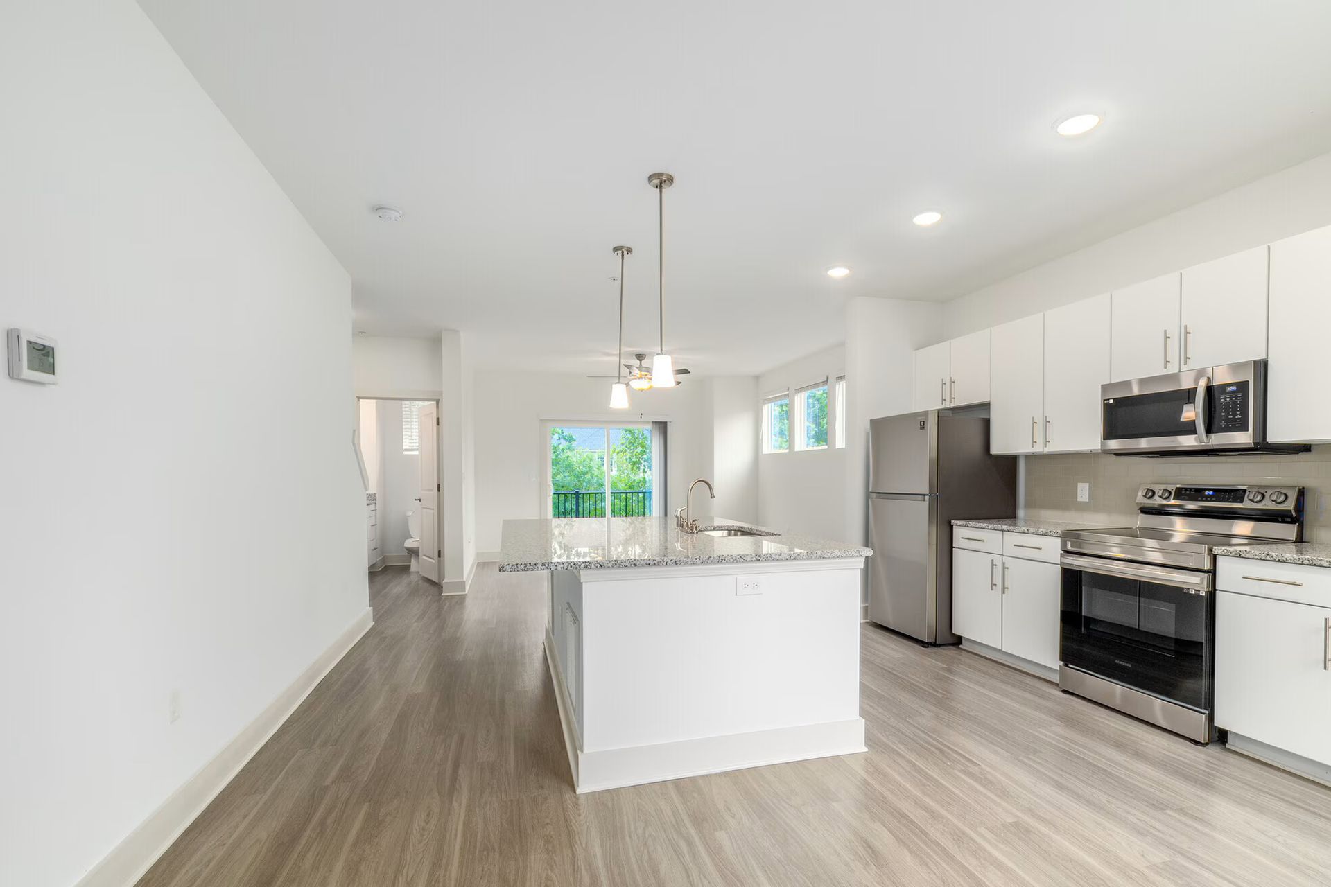 White kitchen with island and stainless steel appliances, light wood floors.