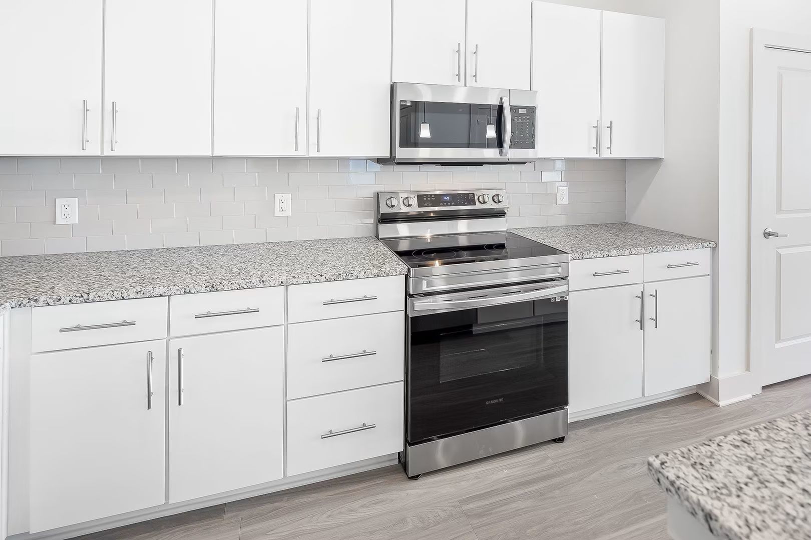 White kitchen with stainless steel appliances and granite countertops.