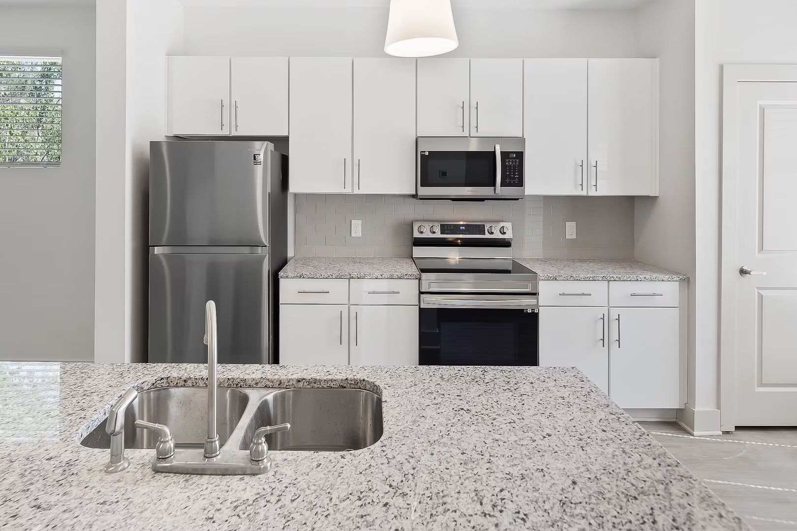 Modern kitchen with stainless steel appliances, white cabinets, and granite countertops.