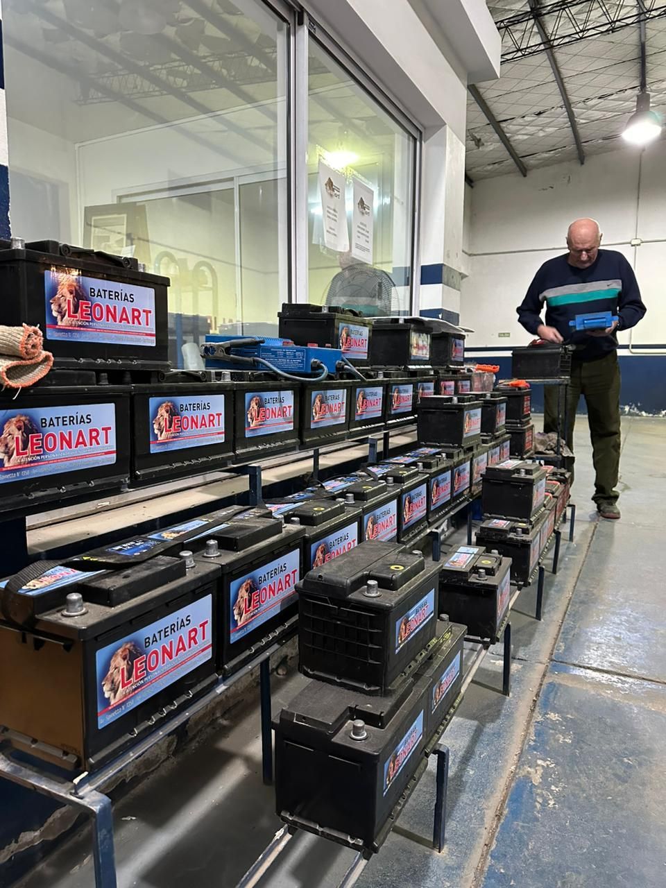 Un hombre está parado frente a una fila de baterías que dicen Leonard.