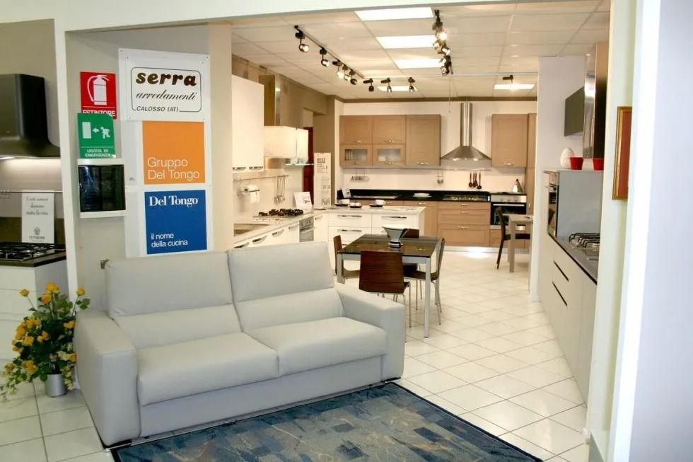 Interno di uno showroom di cucine con cucine in esposizione, un divano e un tavolo.