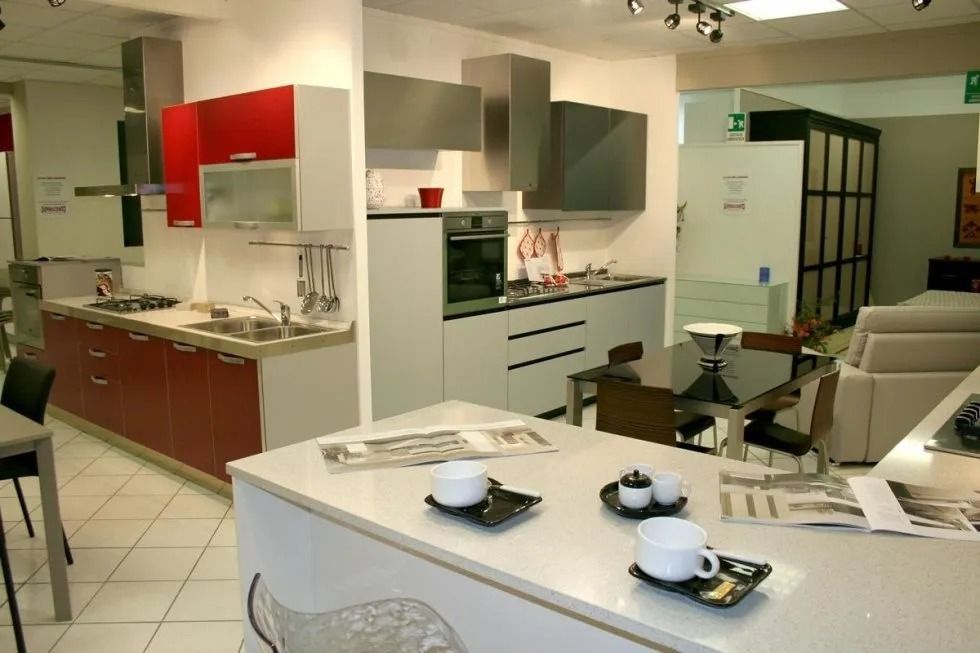 Cucina moderna con mobili rossi e grigi, isola con apparecchiati e zona pranzo.