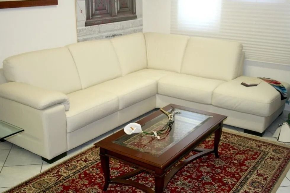 Divano componibile bianco in un soggiorno con tavolino da caffè e tappeto a fantasia.