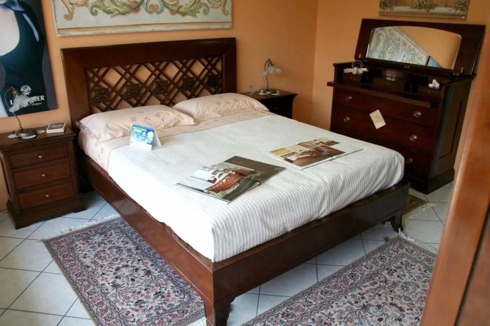 Set di mobili per la camera da letto: letto con testiera a traliccio, cassettiera con specchio, due comodini, tappeti.