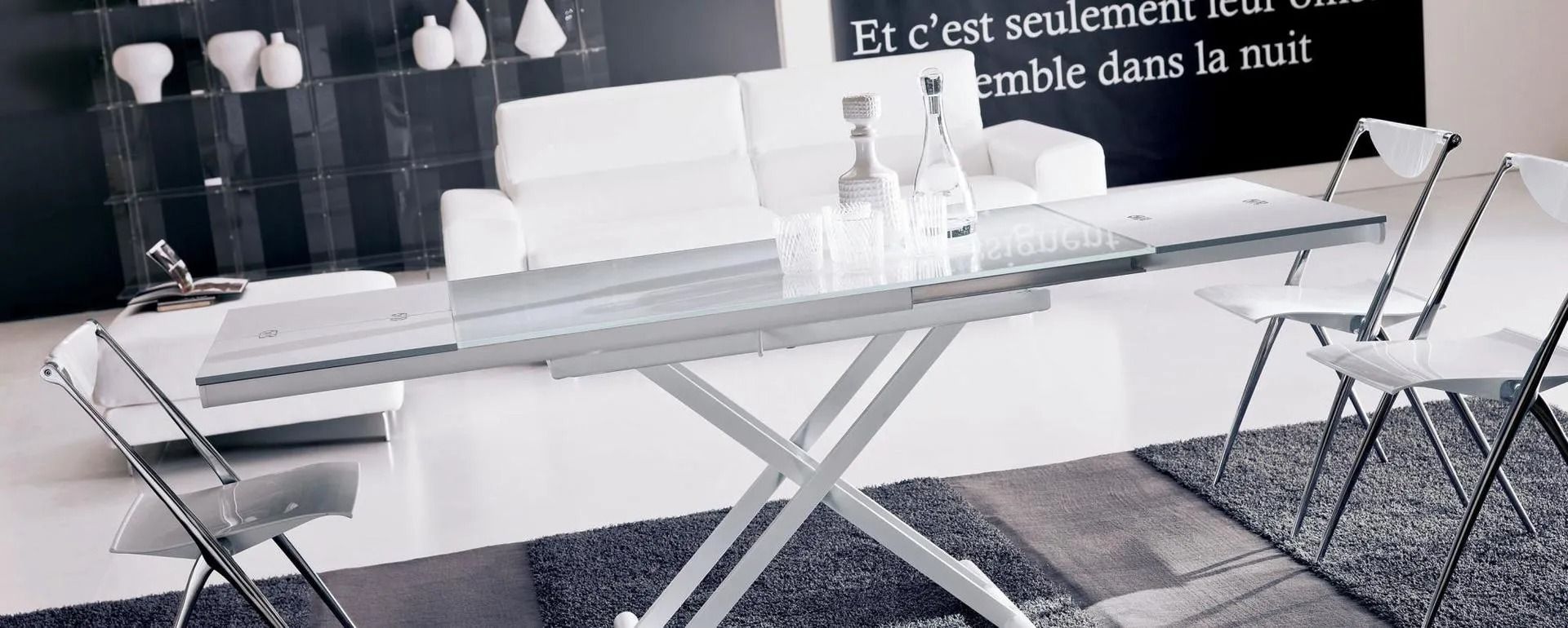 Tavolo bianco con sedie pieghevoli e divano bianco in un ambiente moderno.