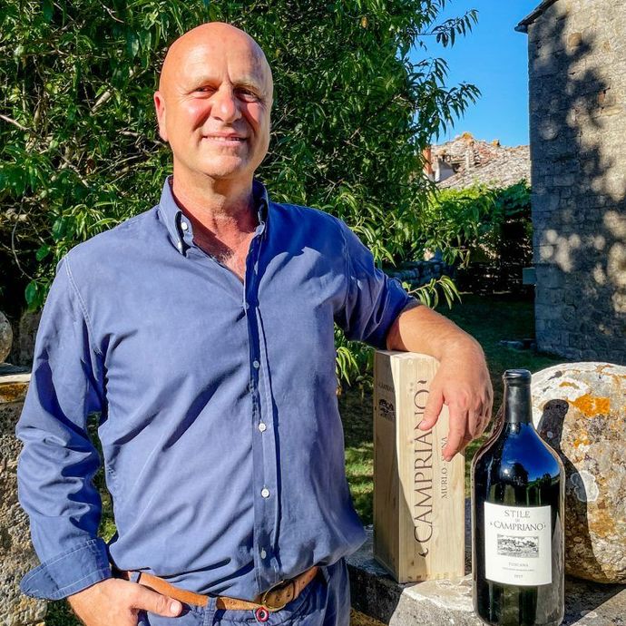 Tre bottiglie di vino su un tavolo all'aperto con uno sfondo sfocato di vigneti verdi.