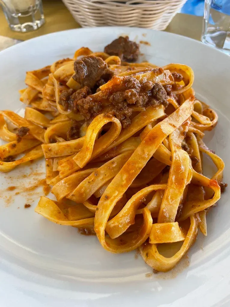 Piatto di tagliatelle al ragù su un piatto bianco a tavola